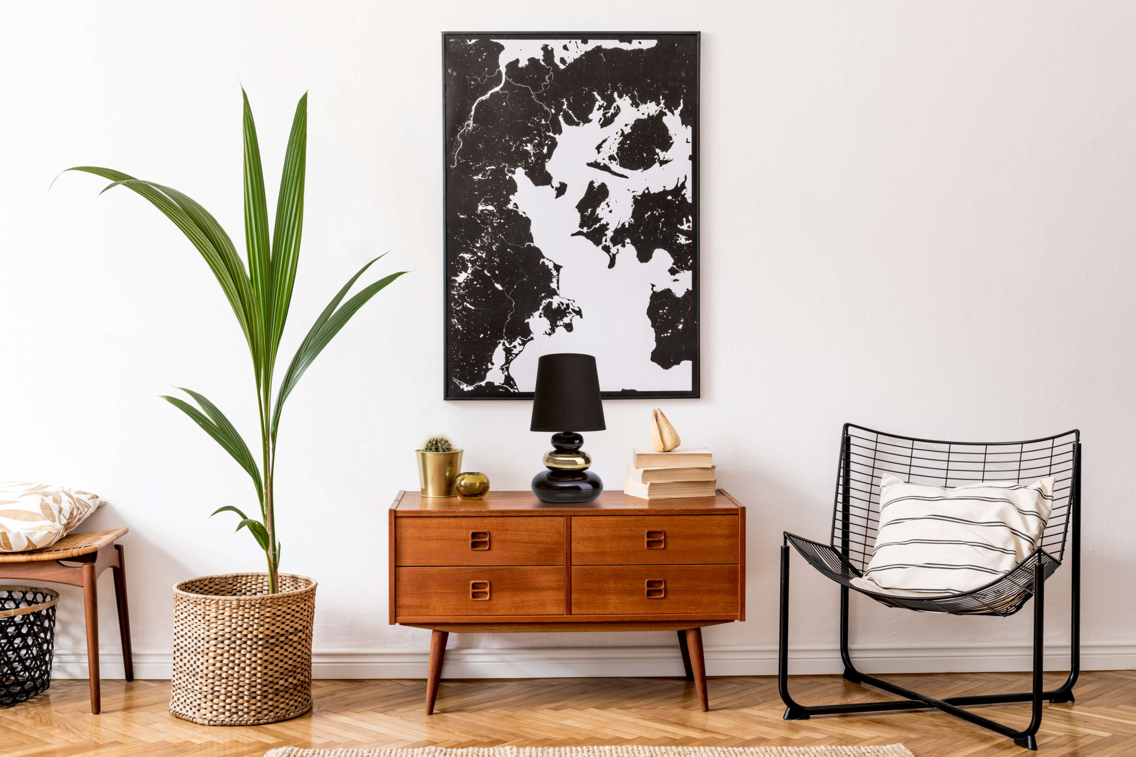 Eine Innenszene im Mid-Century-Modern-Stil. Sie zeigt einen Holzschrank, Kunst und eine Topfpflanze.