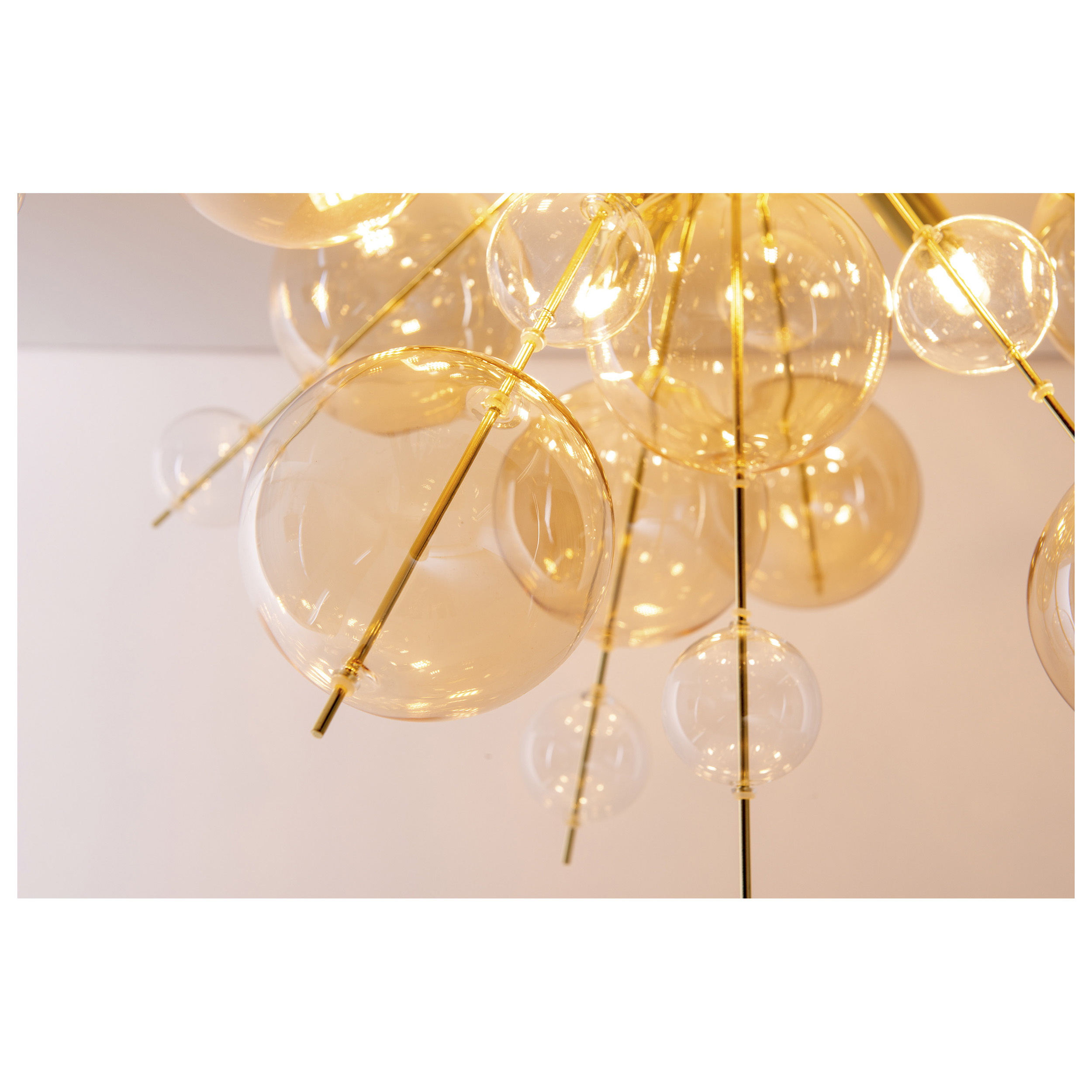 Luminaire de plafond avec de nombreuses ampoules rondes en verre et des tiges en métal doré.