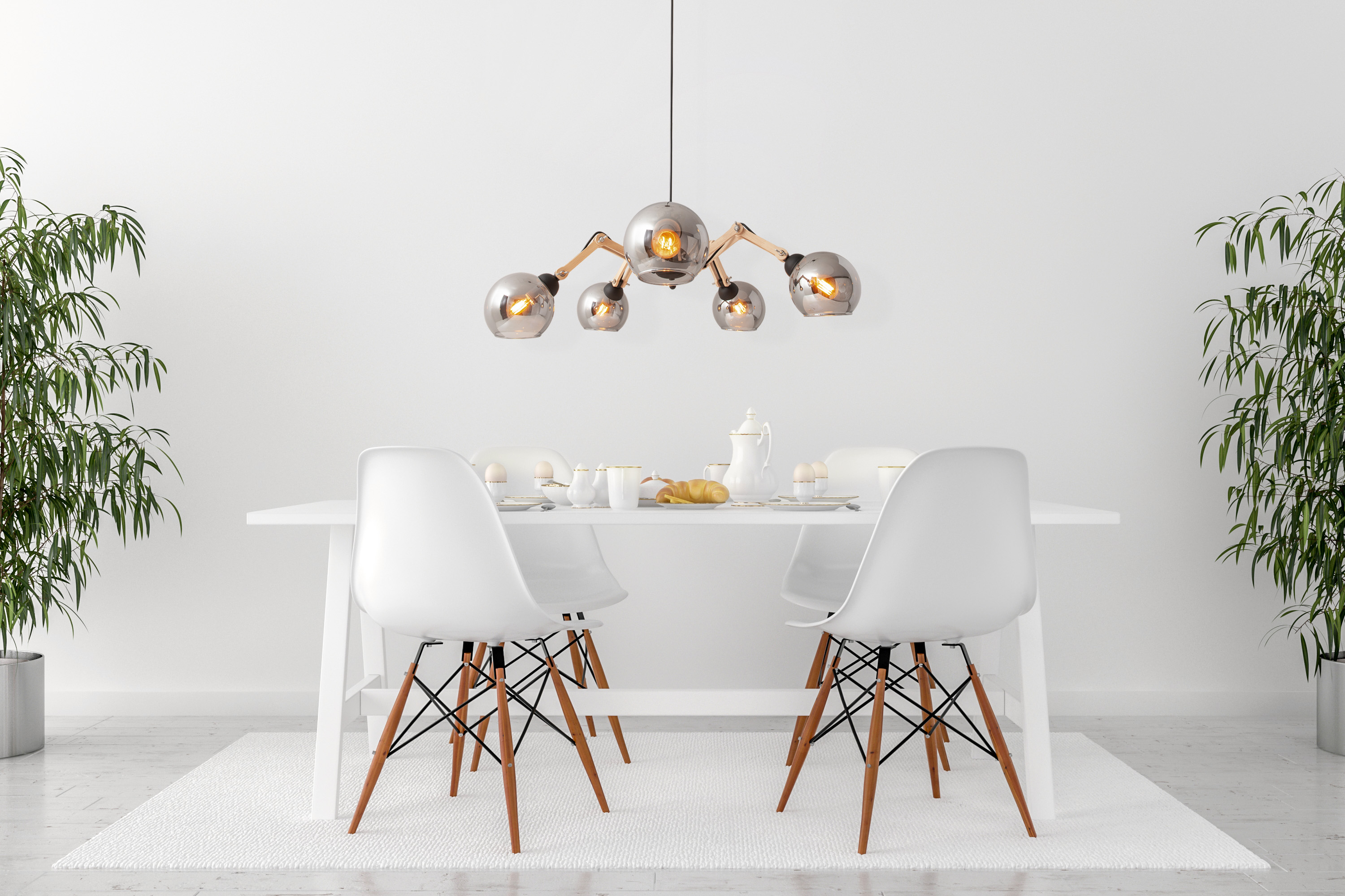 Esszimmer mit weißem Tisch, Stühlen, Pflanzen und Kronleuchter. Weiße Wände und ein weißer Teppich.