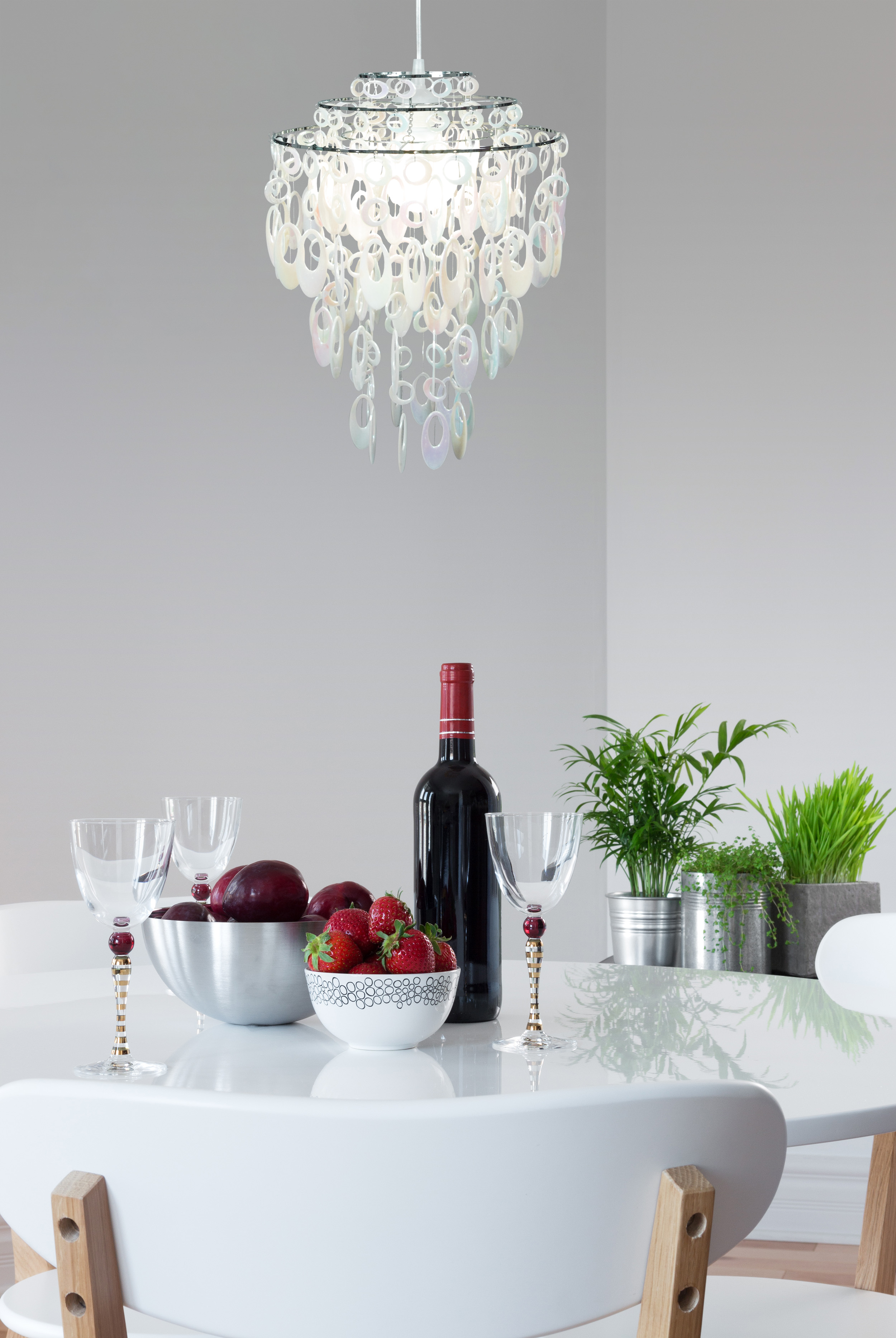 Ein Esstisch mit Kronleuchter, Wein, Gläsern, Obst und Pflanzen.