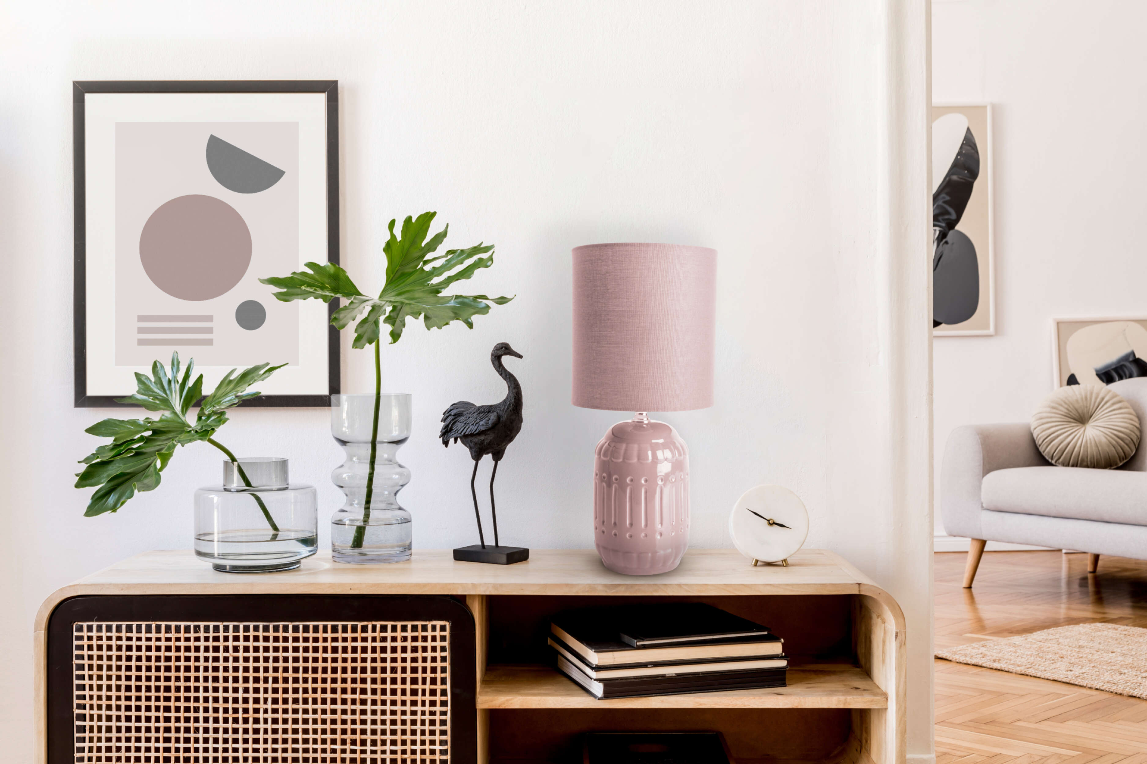 Inneneinrichtung mit Kunst, Lampe und Pflanzen. Rosa Lampe auf einem Holzschrank. Eine Vogelskulptur auch vorhanden.