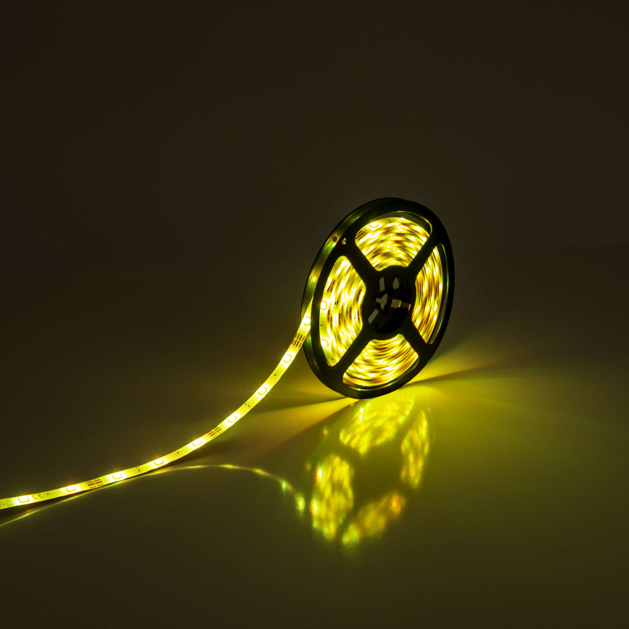Eine Rolle gelber LED-Streifen. Die Lichter sind auf einer schwarzen Kunststoffrolle aufgewickelt und werfen einen gelben Schein.
