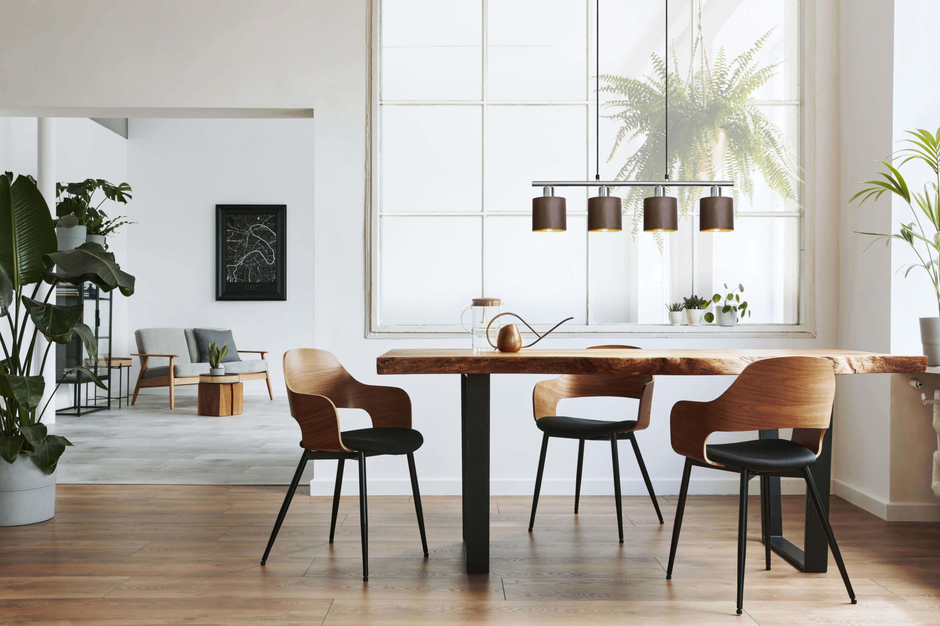 Esszimmer mit Holztisch, Stühlen und Pendelleuchte. Pflanzen und Sonnenlicht.