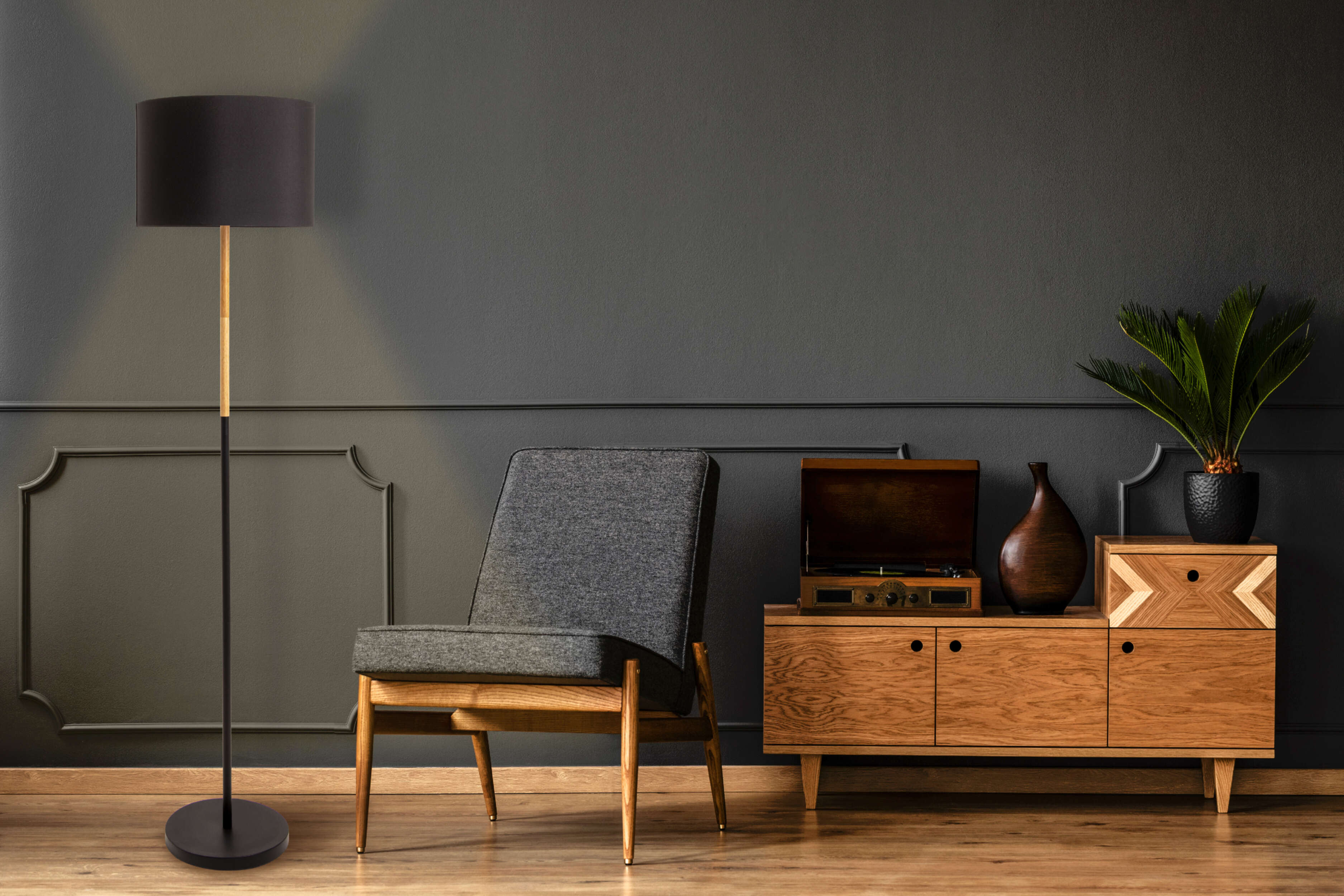 Une lampe avec un abat-jour noir, une tige dorée et un meuble en bois.