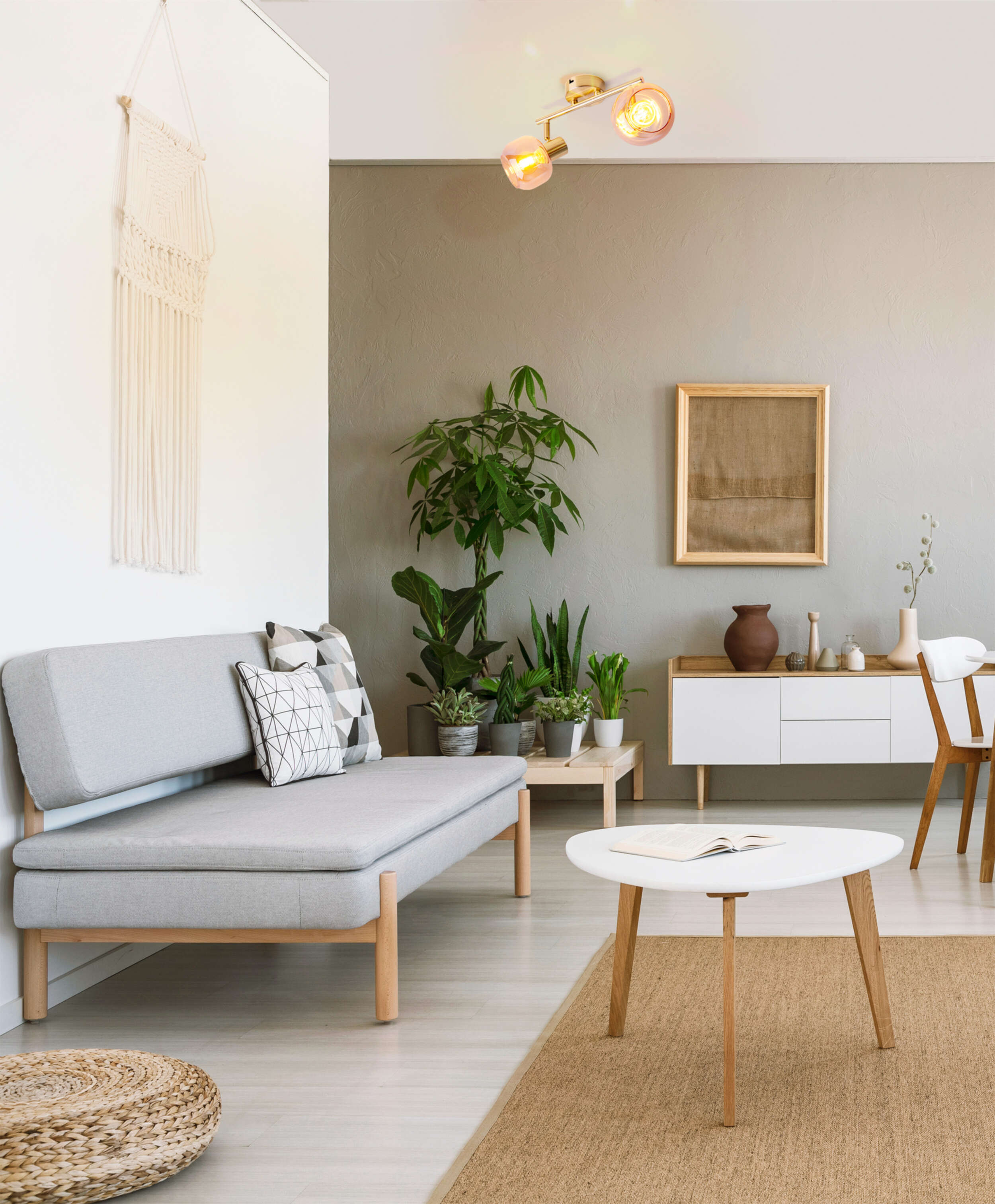 Wohnzimmerszene: graues Sofa, weißer Tisch, Pflanzen, ein Gemälde und eine Deckenleuchte.