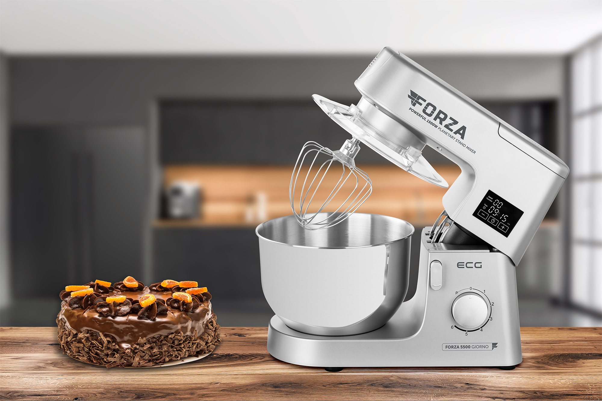 Ein silberner Küchenmixer mit Kuchen. Ein Kuchen steht neben dem Mixer auf dem Tisch.