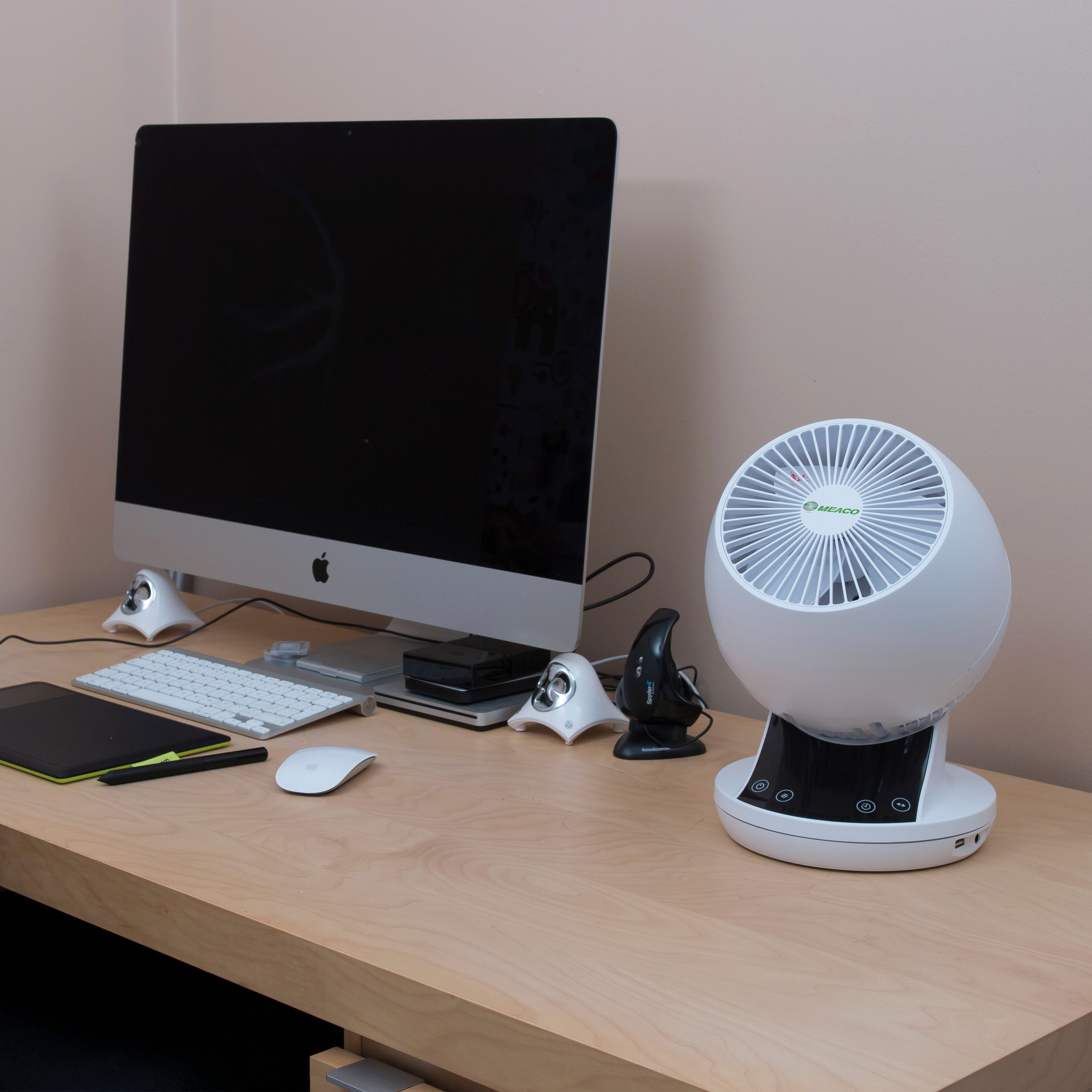 Schreibtisch mit Computer, Ventilator und anderer Büroausstattung.