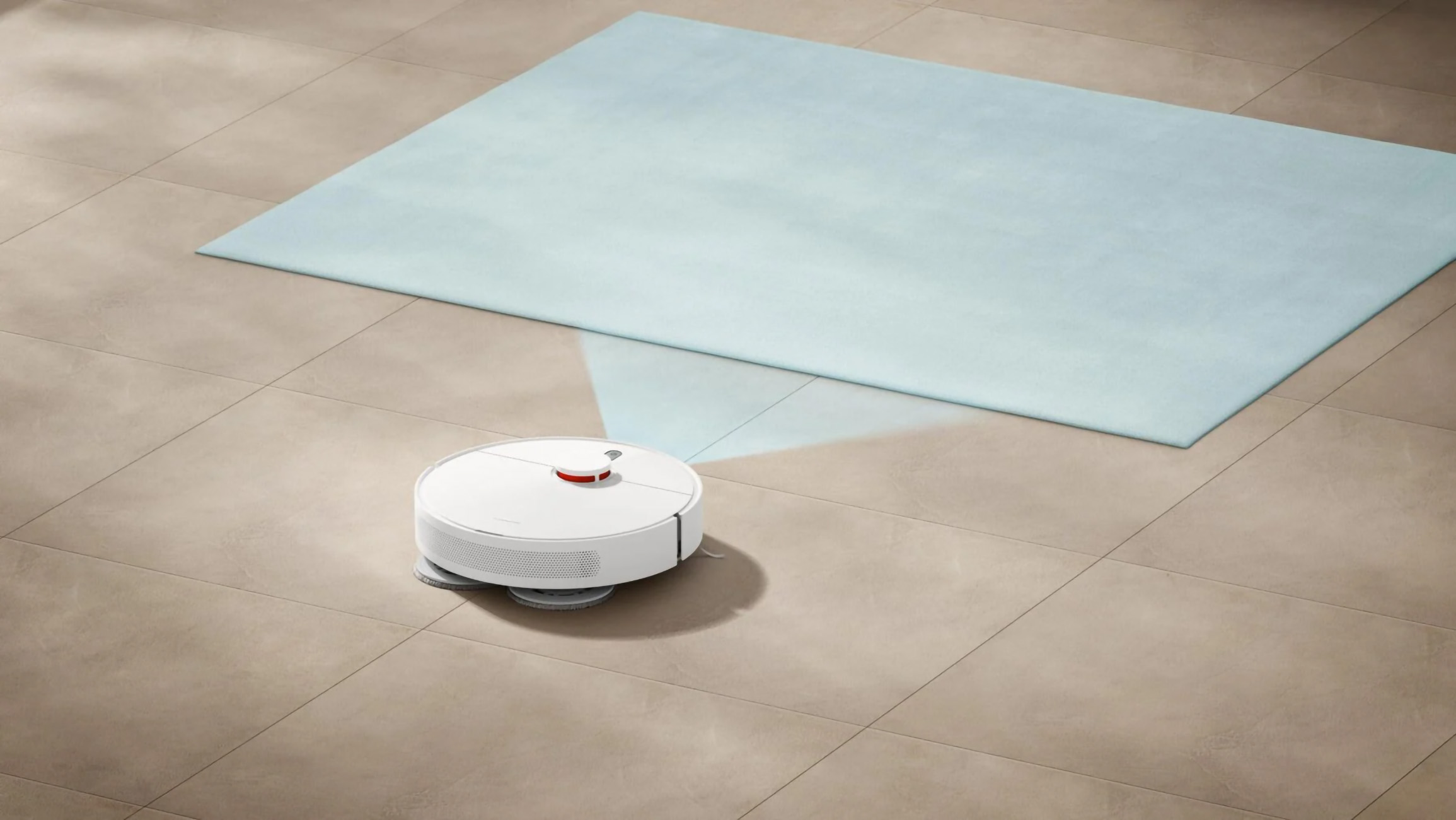 Beyaz bir robot süpürge fayanslı zeminde. Arka planda mavi bir halı var.