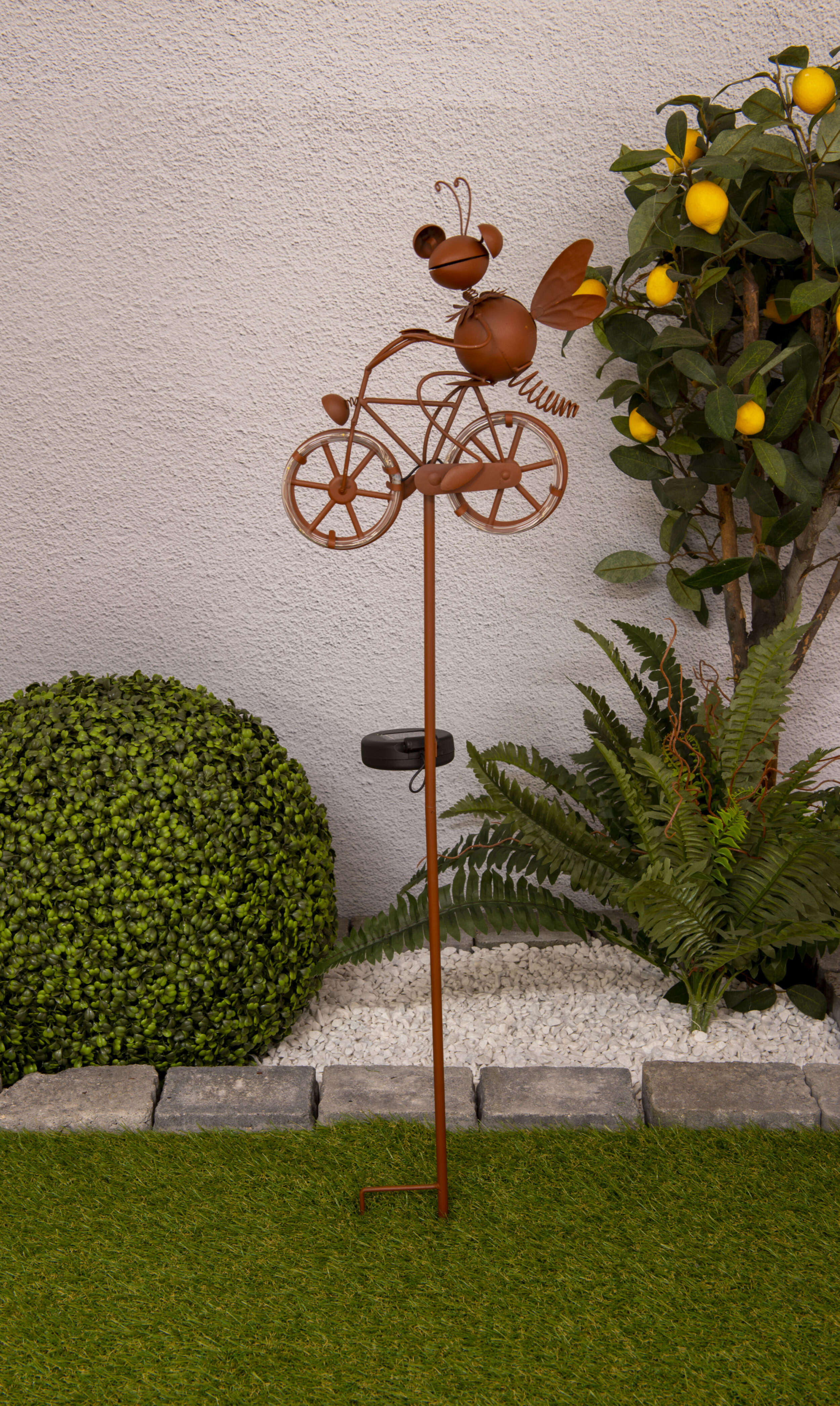 Solar LED-Gartenornament einer Biene, die Fahrrad fährt, mit einem Zitronenbaum im Hintergrund.