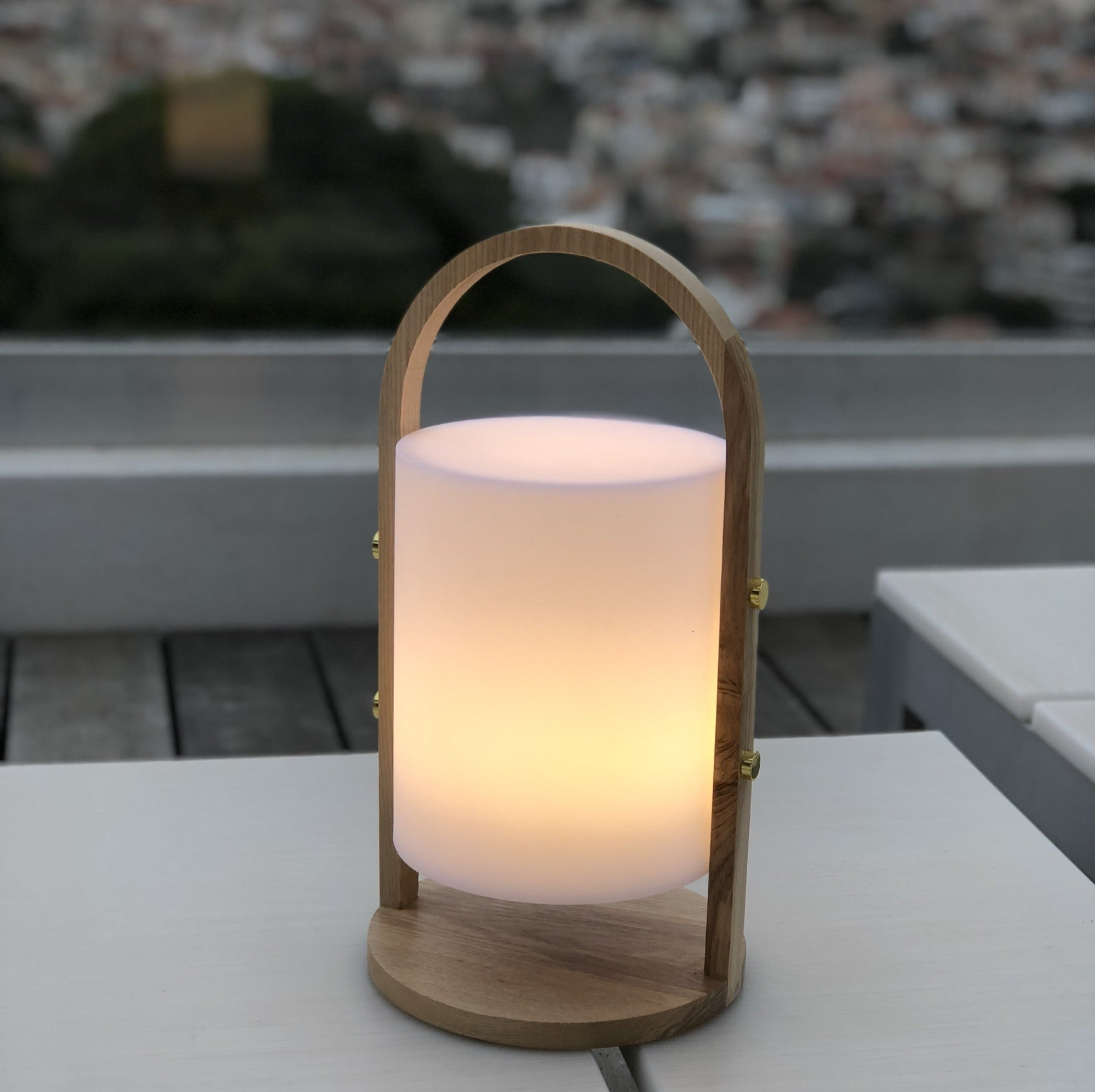 Holzlaterne mit weißem Licht im Inneren. Auf einem weißen Tisch stehend.
