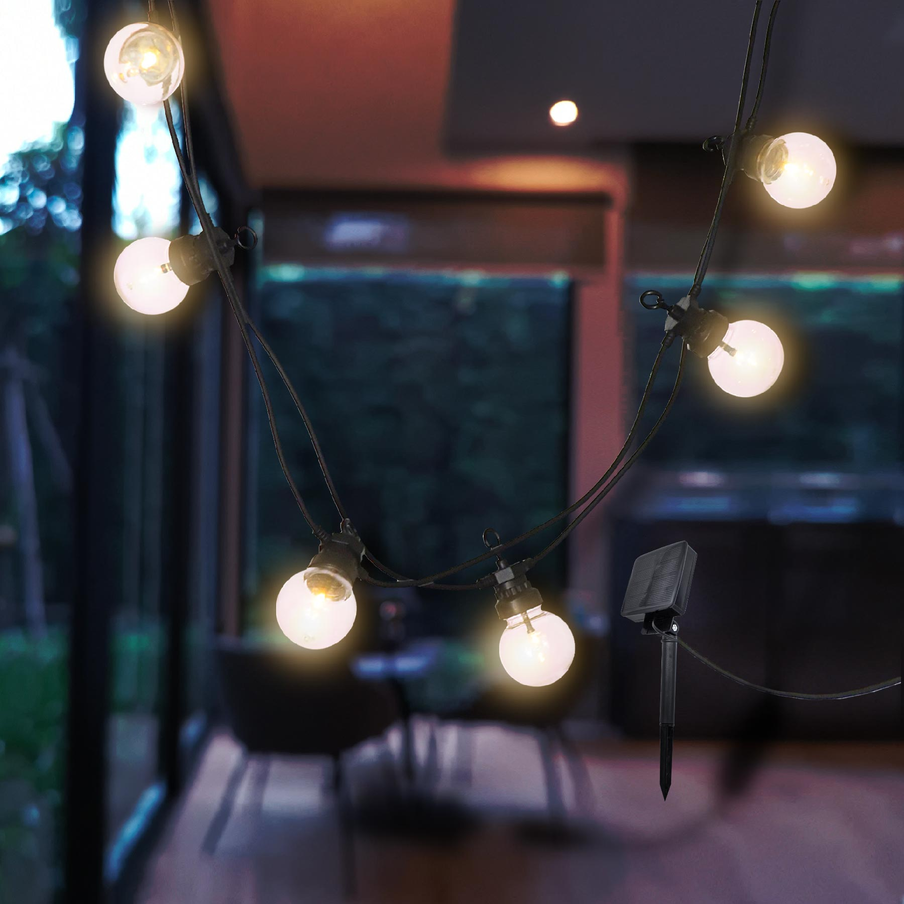 Lichterkette mit Glühbirnen, hängend, mit Solarpanel im Hintergrund.