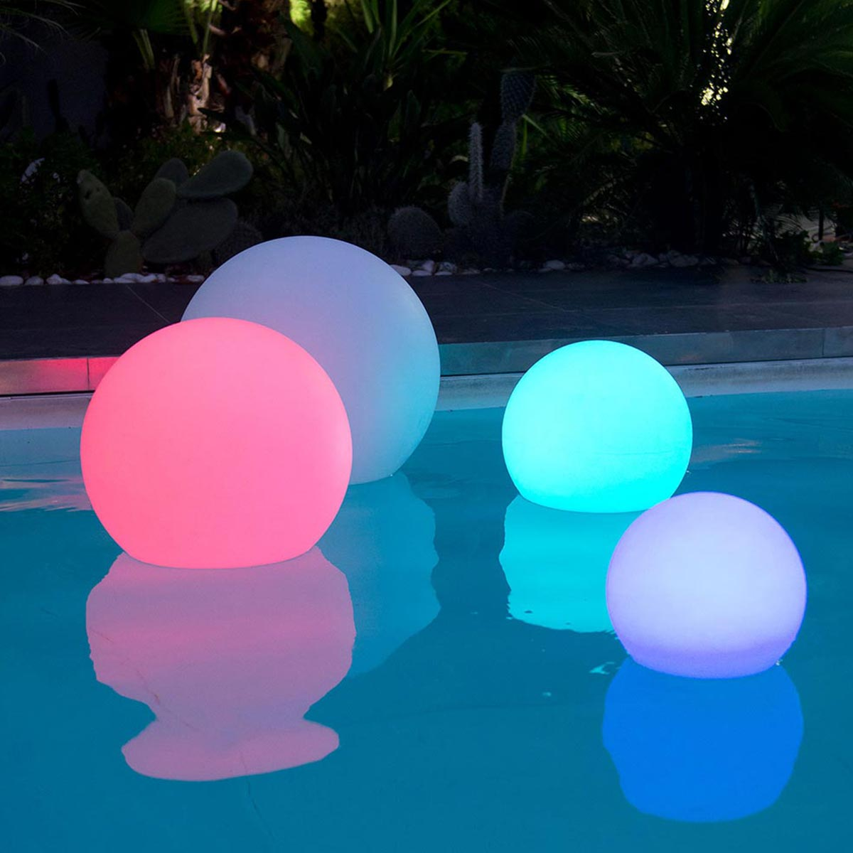 Schwimmende, beleuchtete Kugeln in einem Pool. Verschiedene Farben.