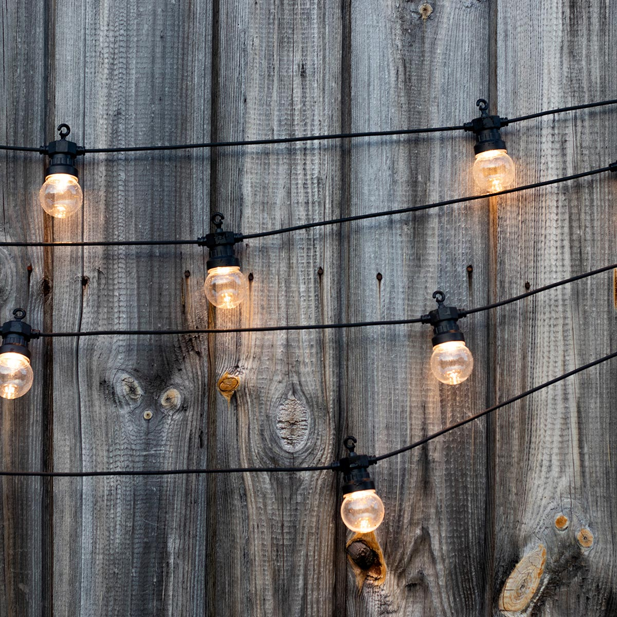 Lichterkette hängt an einer Holzwand mit Holzstruktur.