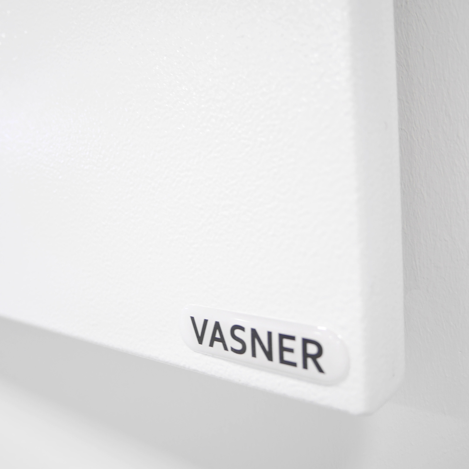 Weißes Panel mit dem Markennamen VASNER. Nahaufnahme, klar und einfach. Weißer Wandhintergrund.