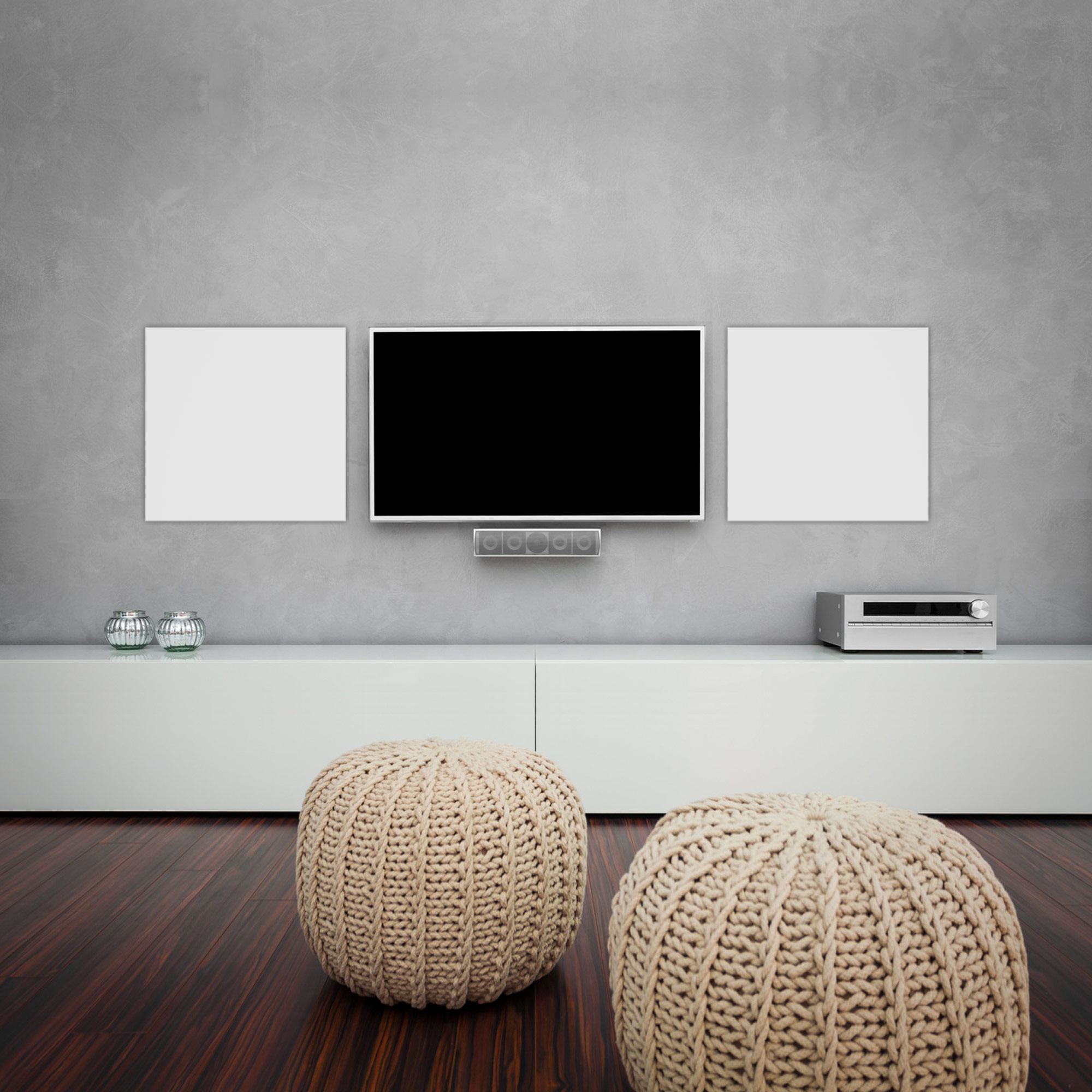 Wohnzimmer-Setup mit TV, weißem Schrank und zwei beigen Sitzsäcken vor grauer Wand.