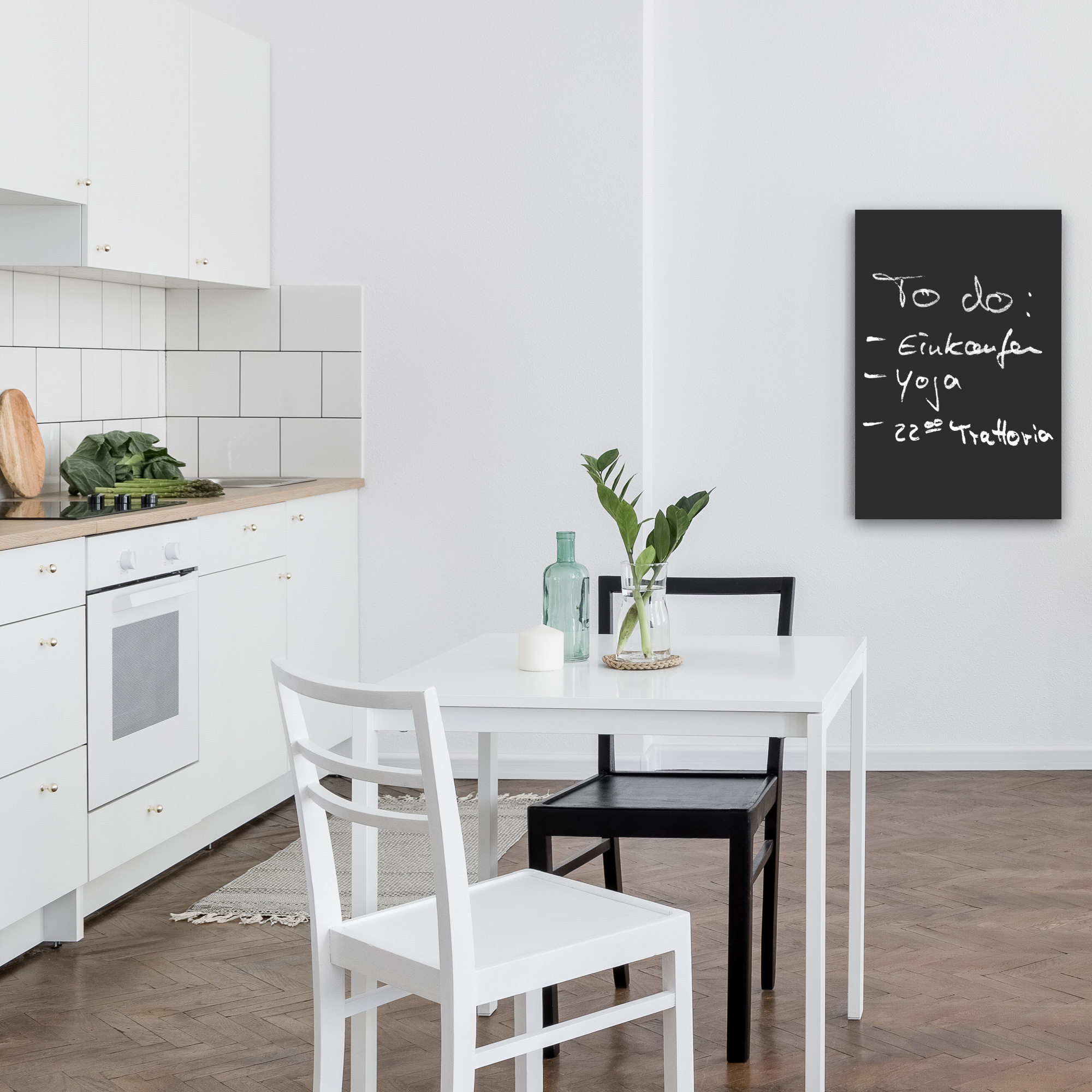 Eine moderne Küche mit Tisch, zwei Stühlen, einer Tafel und einem Blick auf die Küche.