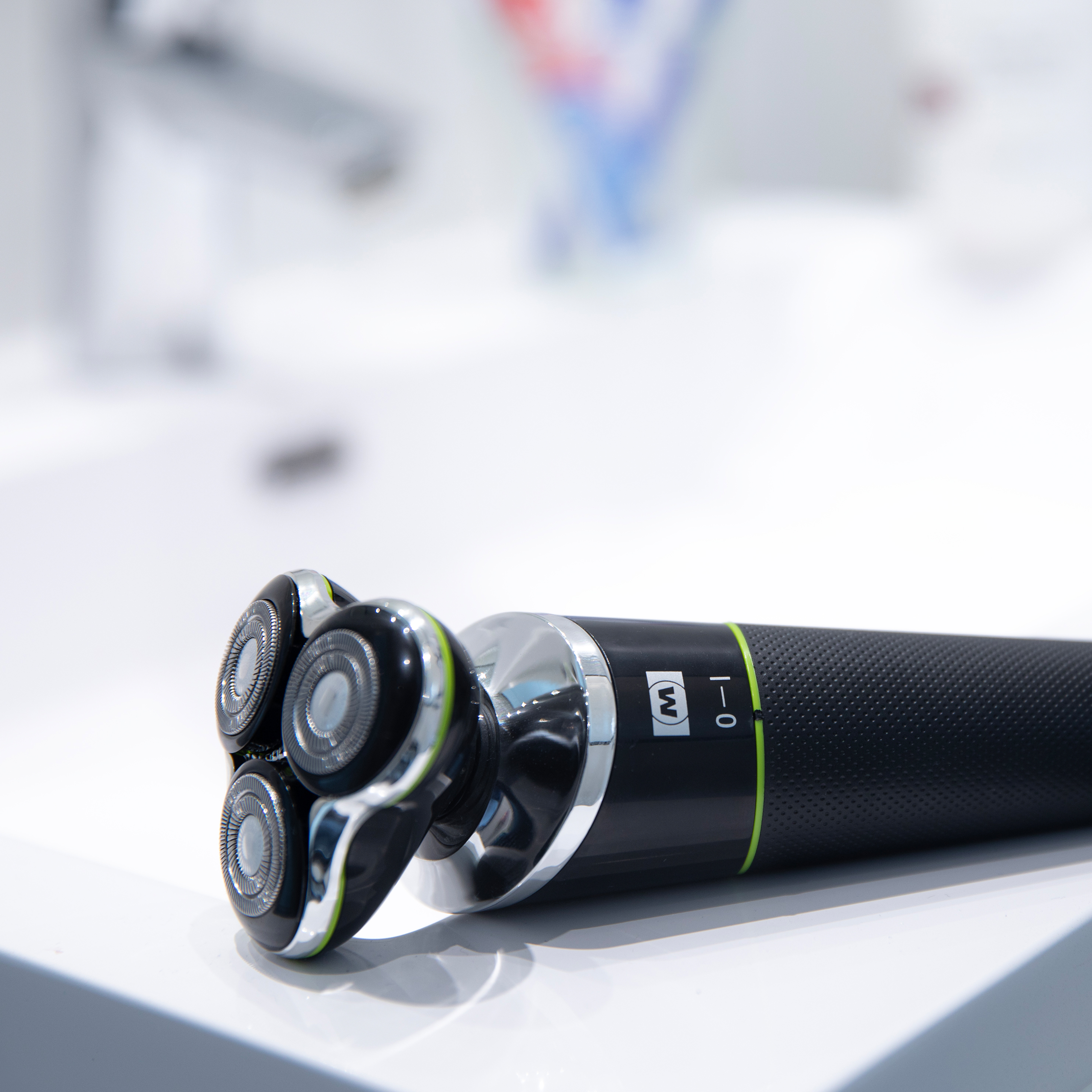 Czarno-srebrna golarka elektryczna z trzema obrotowymi głowicami, na białej powierzchni.