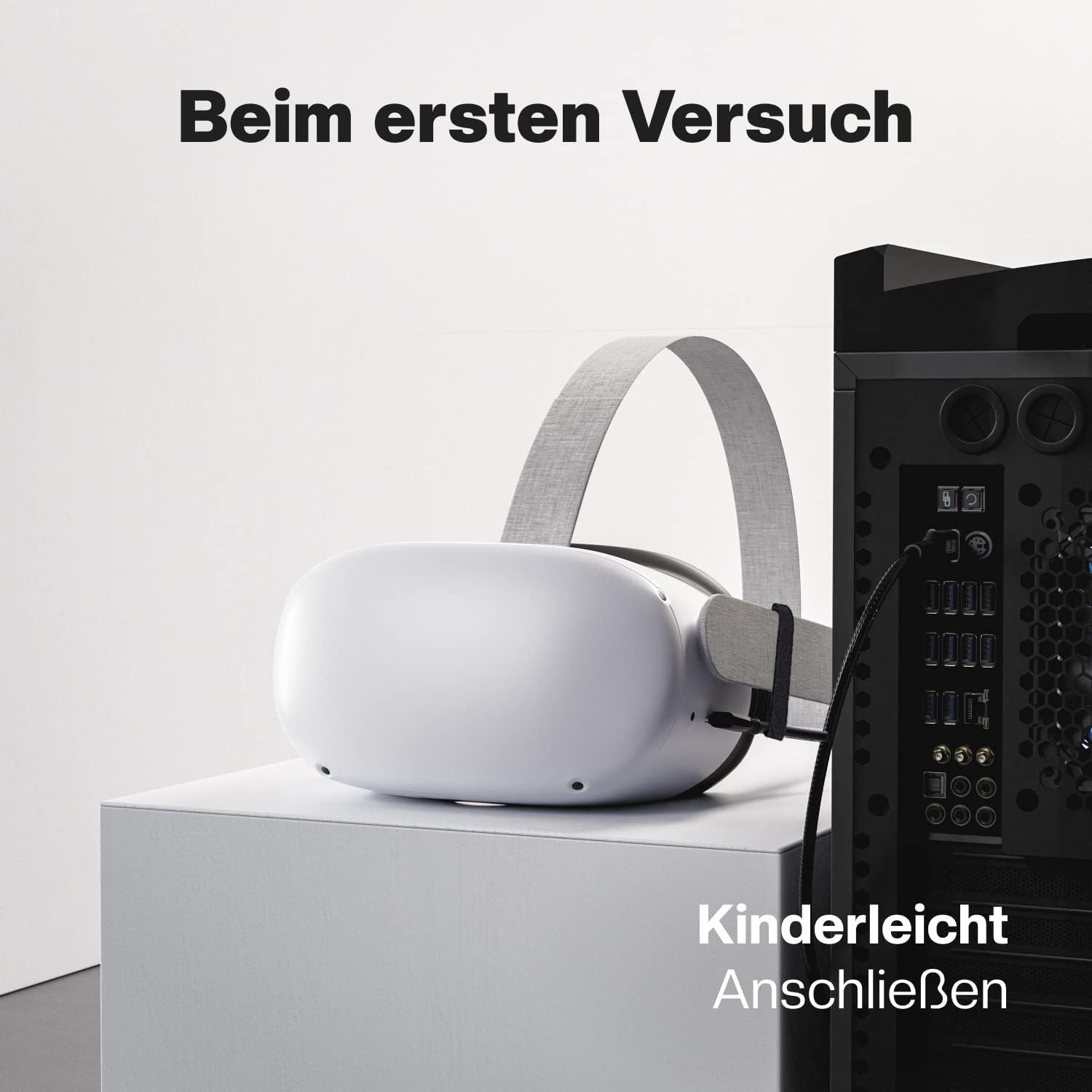 Ein VR-Headset auf einem weißen Würfel, neben einem Computer, mit Text auf Deutsch.