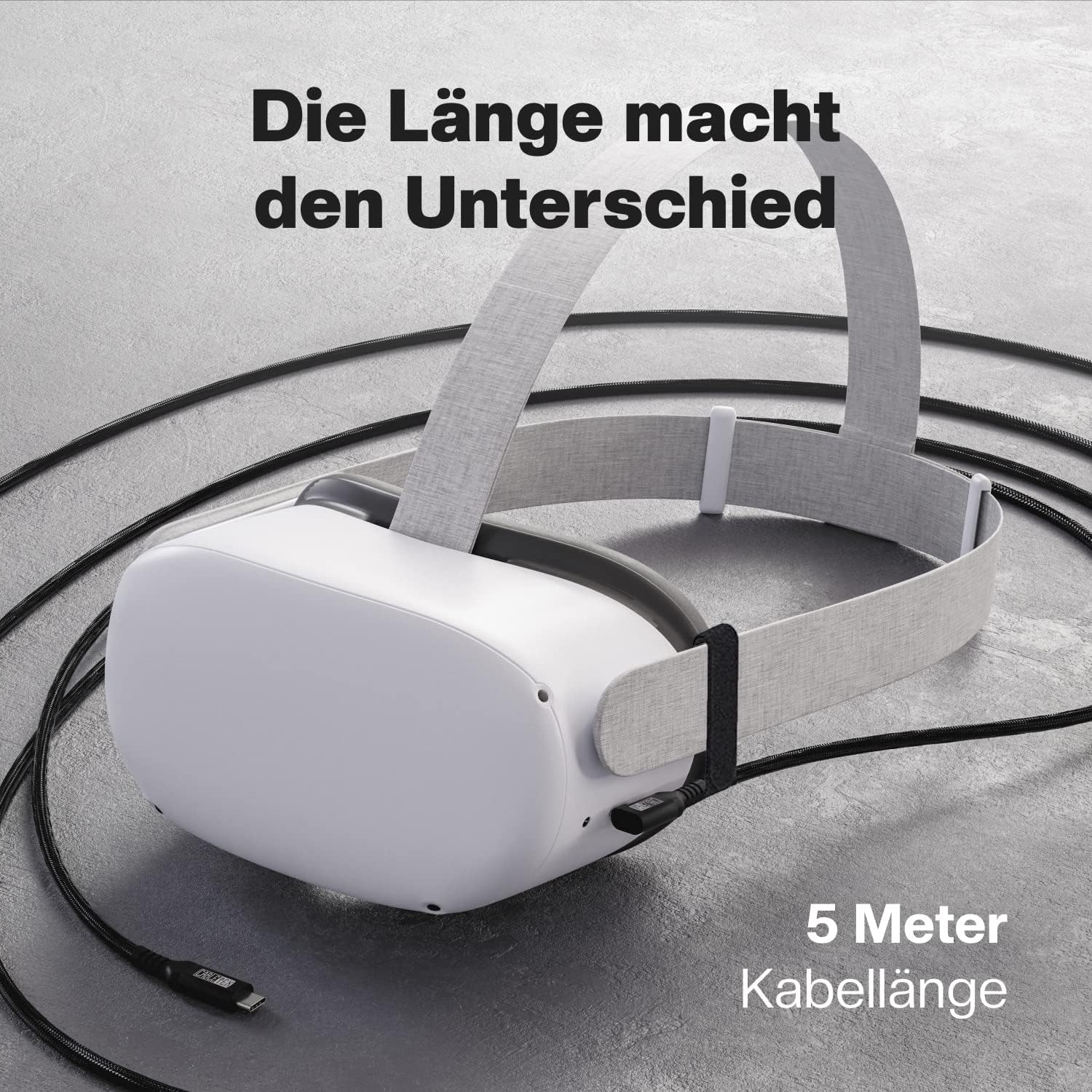 Ein VR-Headset mit Kabel. Text: „Die Länge macht den Unterschied“. Es liegt auf einer grauen Oberfläche.