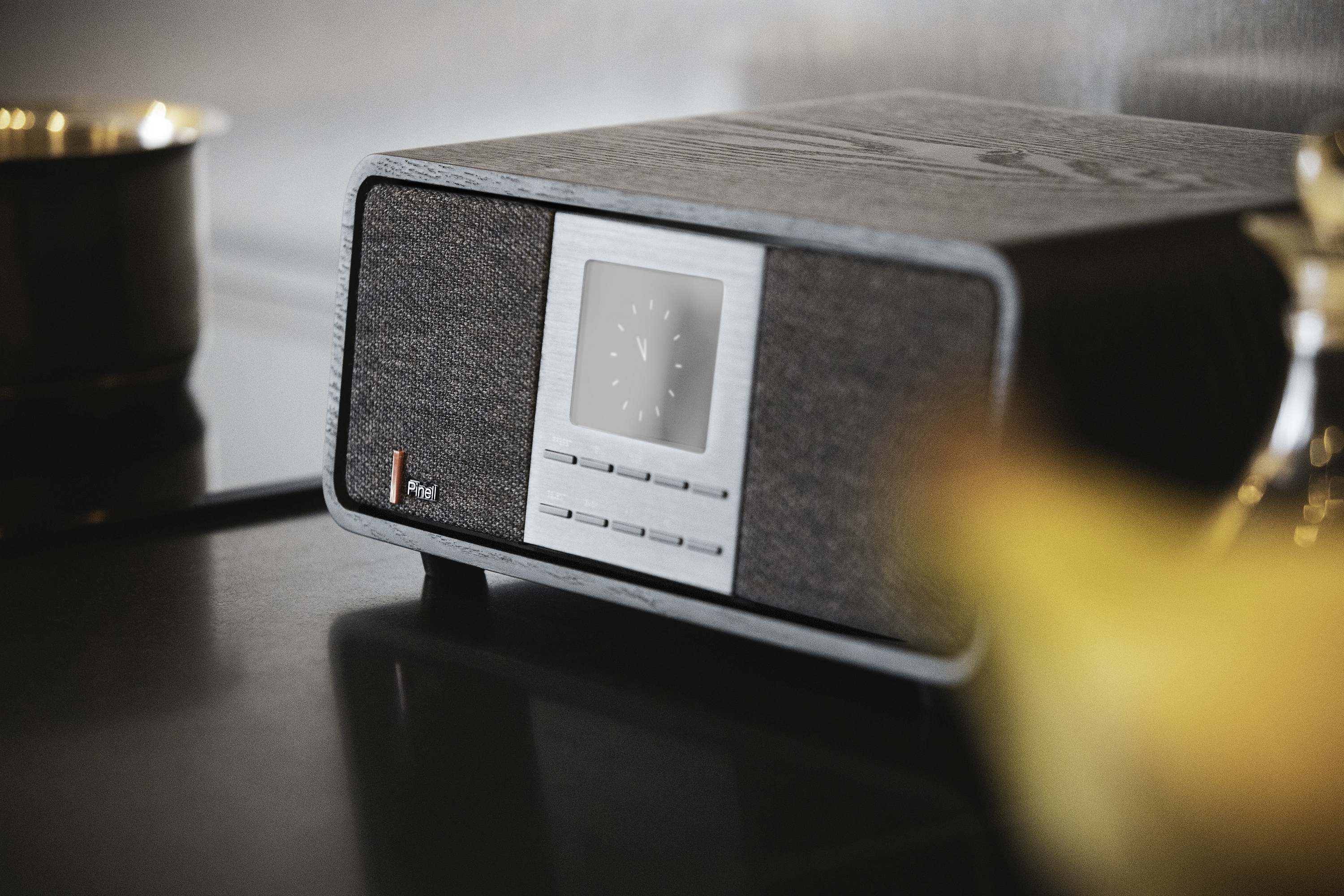 Retro-style radio on a black surface. Features a digital clock, silver accents, and a fabric front.