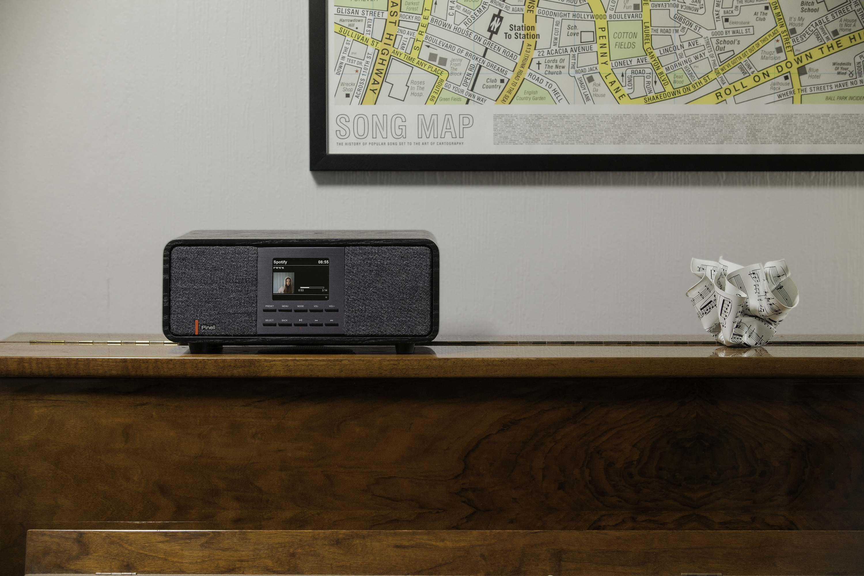 Black speaker on piano. A map is in the background. White paper notes on the right.