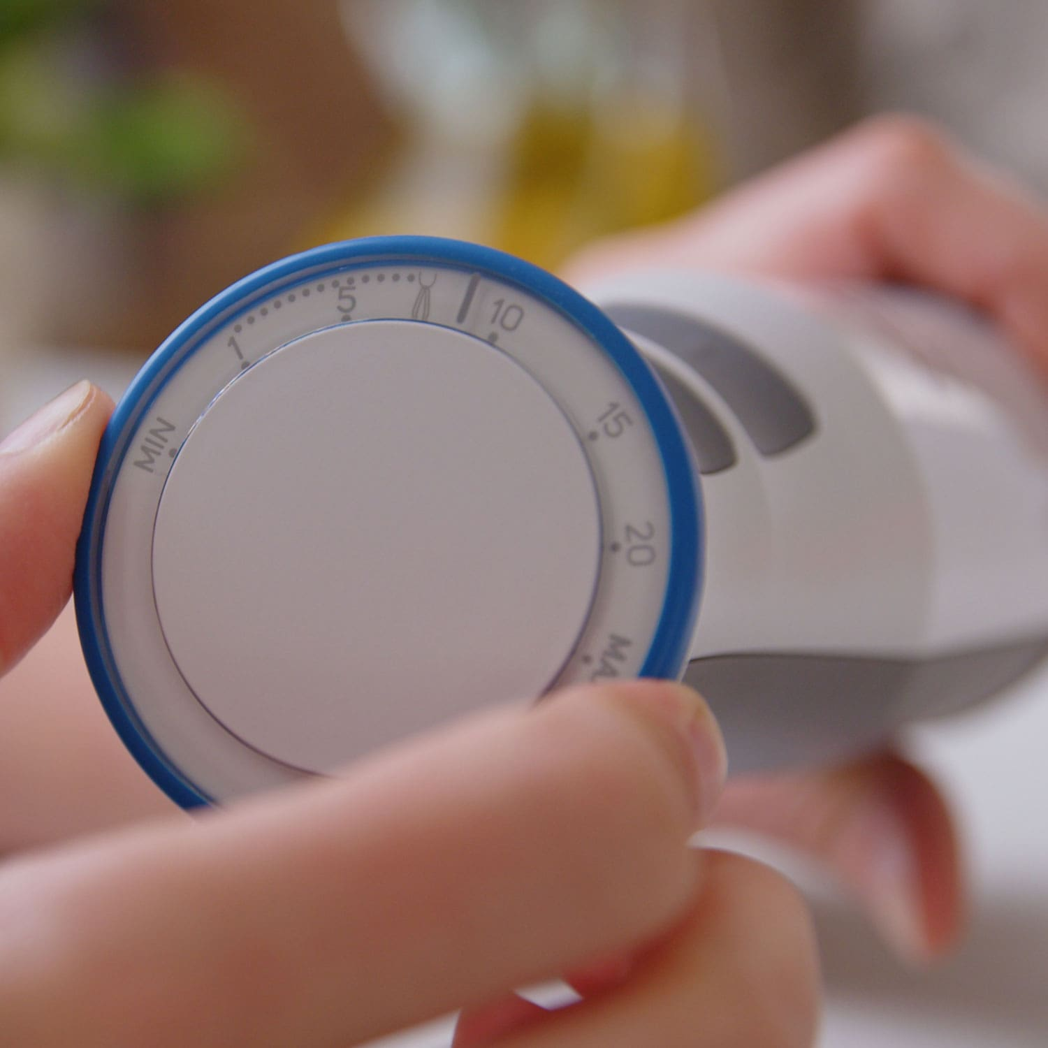 Las manos de una persona ajustando un dial de temporizador azul y blanco con números.