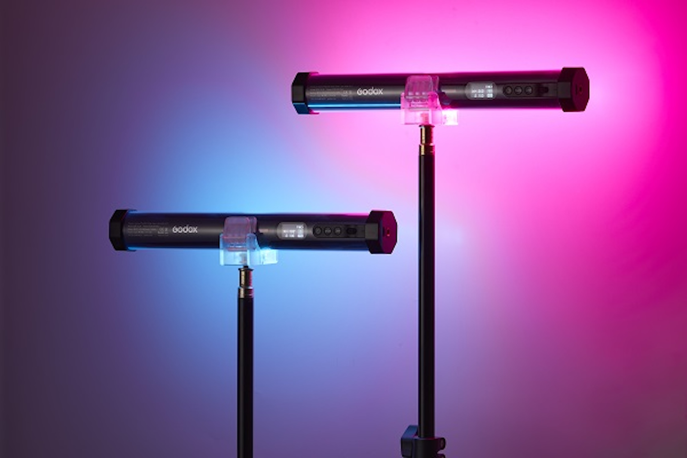 Zwei schwarze zylindrische Lichter auf Ständern, mit einem lila-blauen Farbverlauf im Hintergrund.