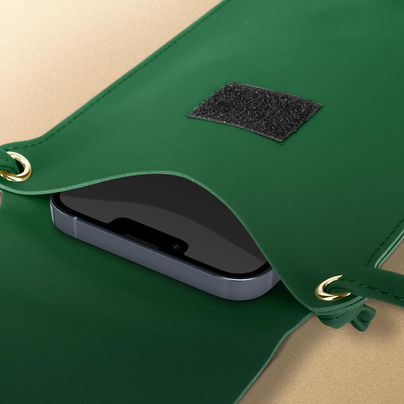 Grüne Telefontasche mit Telefon. Schwarzer Riemen, goldene Ösen. Telefon ist schwarz.