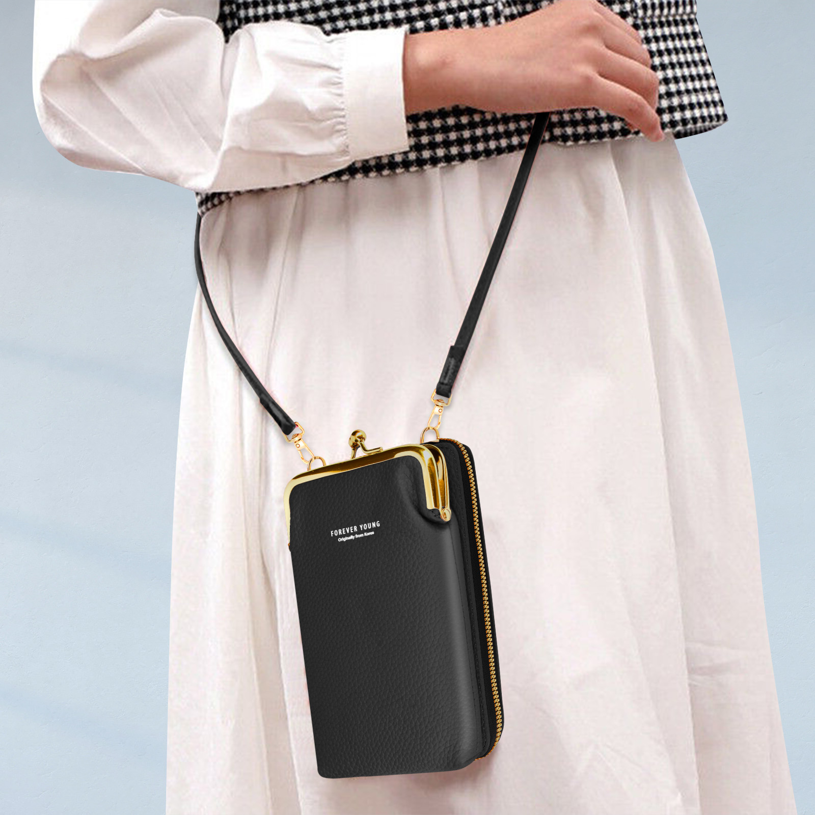 Een vrouw houdt een zwarte, rechthoekige crossbodytas vast met een gouden sluiting en riem.
