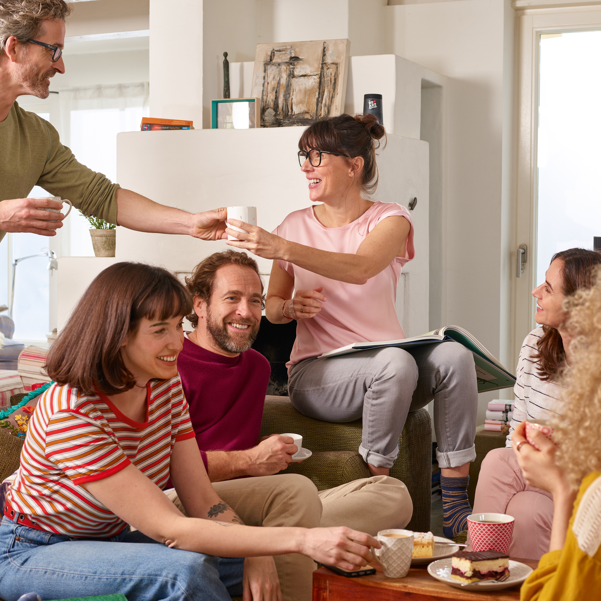 Eine Gruppe von Menschen an einem Tisch, die Essen und Getränke teilen, lächeln und interagieren.