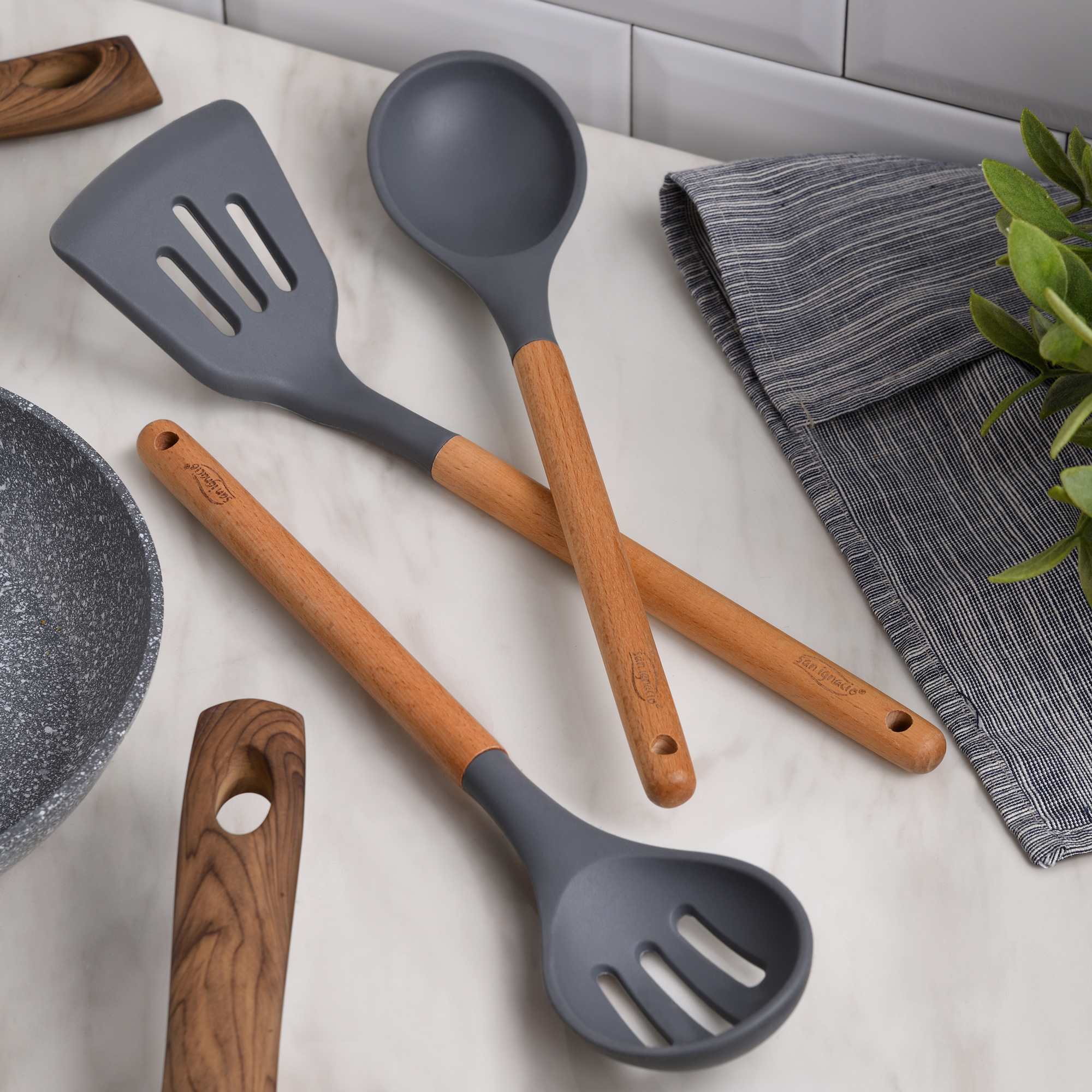 Utensilios de cocina: una espátula ranurada, una cuchara y una cuchara ranurada con mangos de madera.