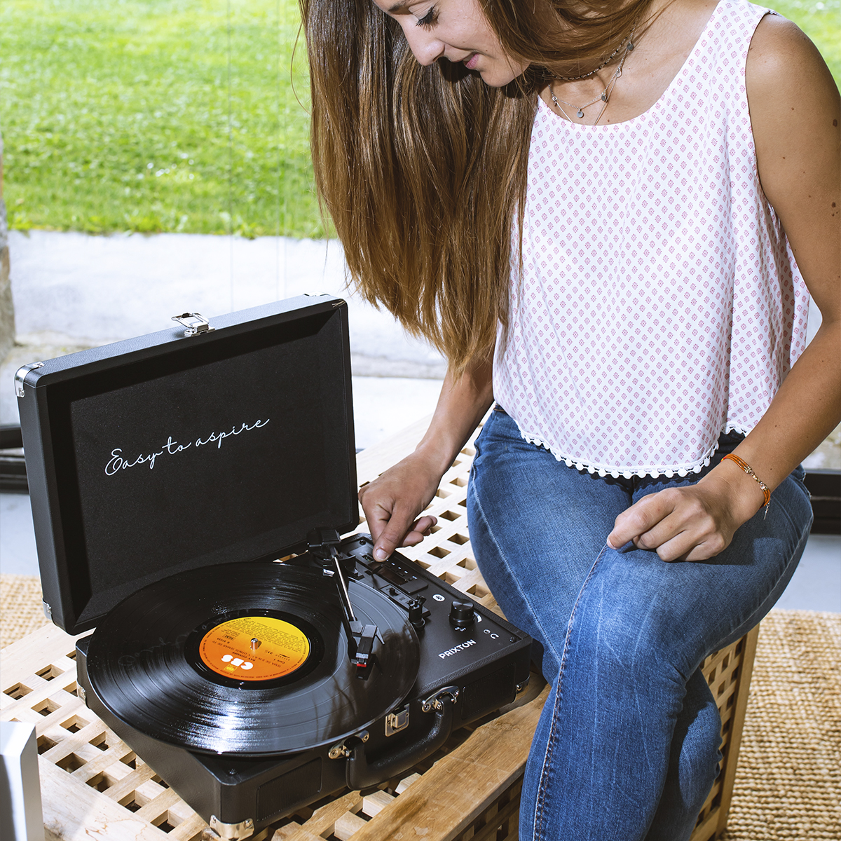 Kobieta używa gramofonu. Czarna płyta na talerzu, a tekst brzmi 'Easy to aspire'.