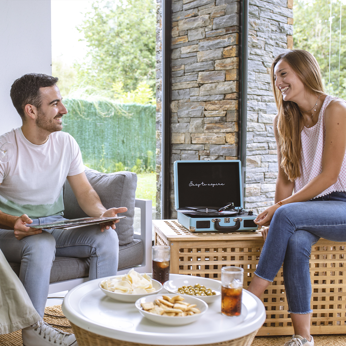 Dwie osoby pijące napoje i przekąski, słuchające gramofonu. Słoneczny dzień.