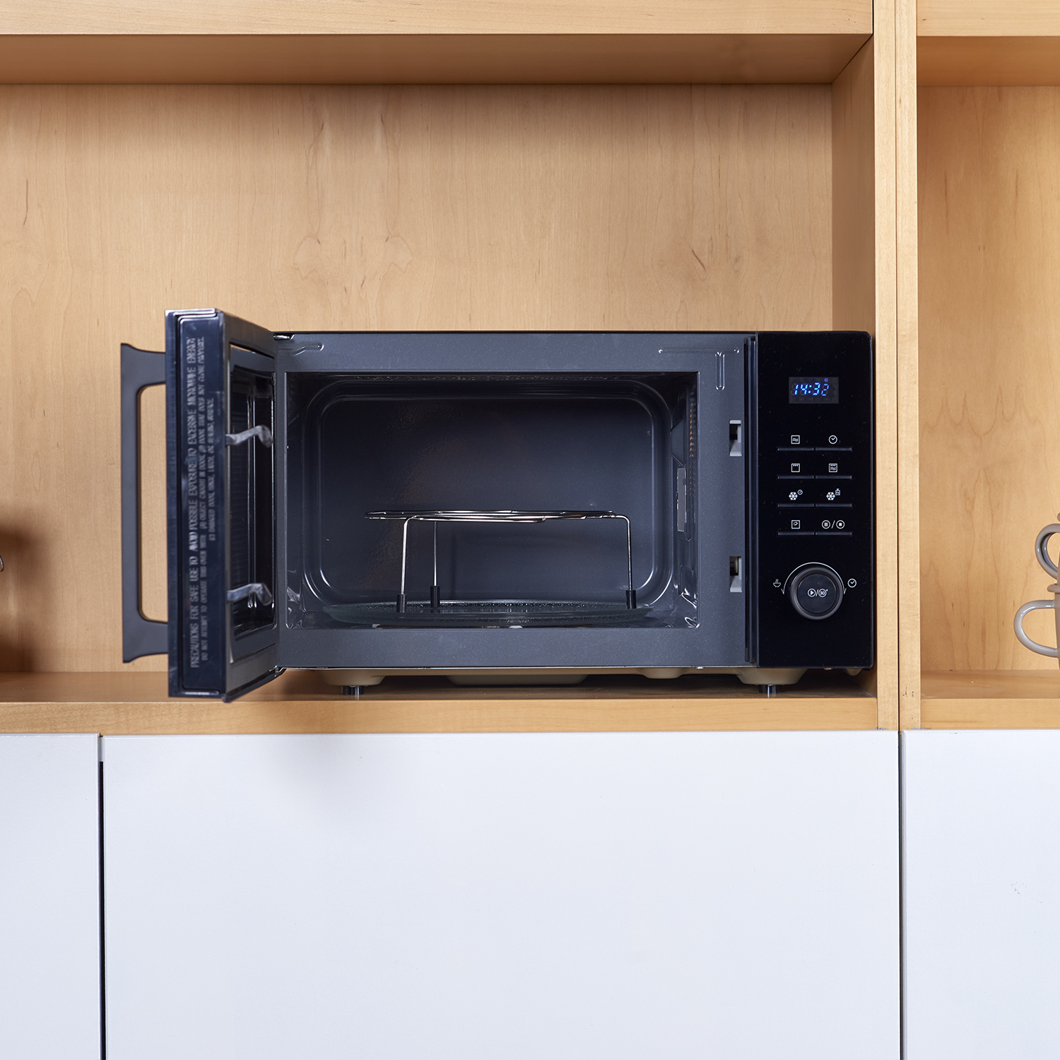 Un horno microondas negro dentro de un armario de madera con la puerta abierta.