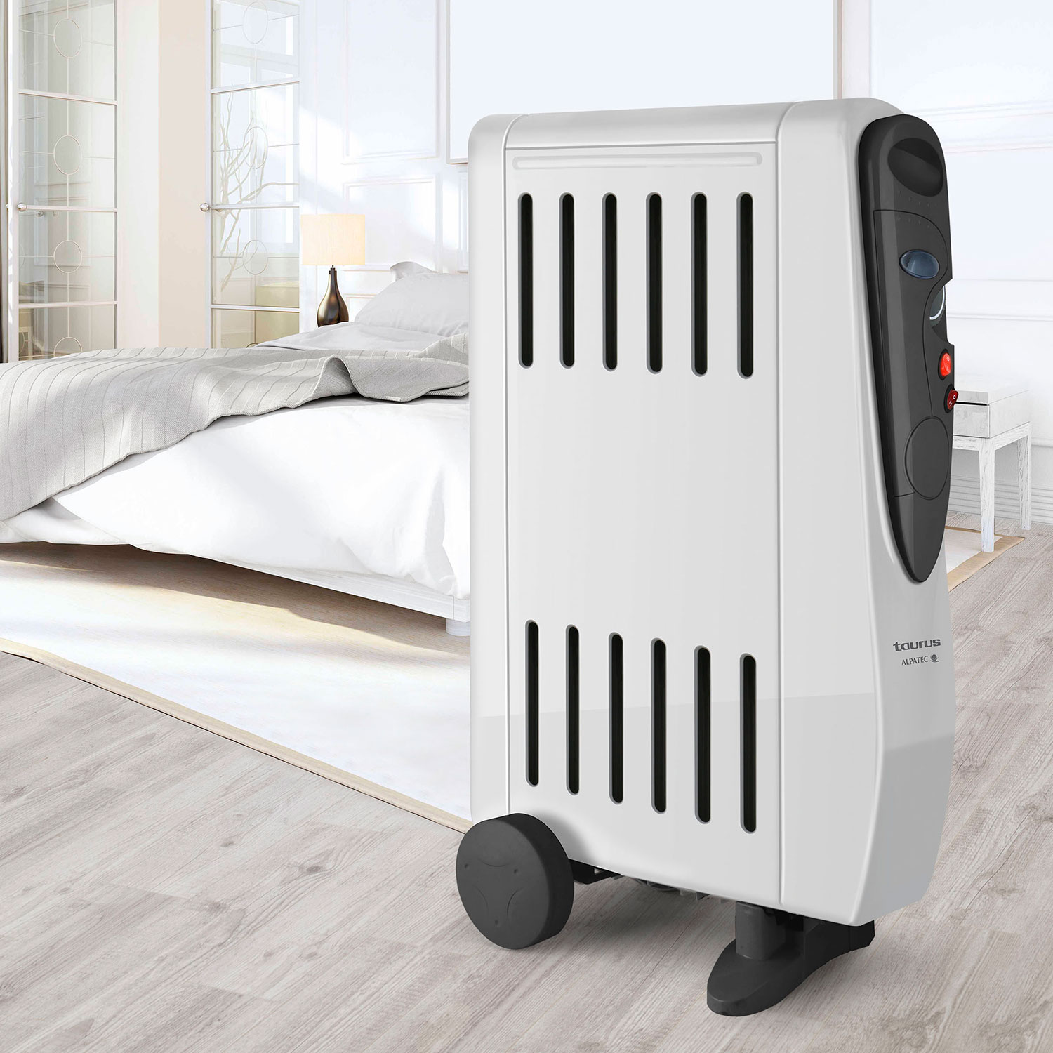 Ein weißer Ölradiator befindet sich in einem Schlafzimmer mit Bett und Beistelltisch.