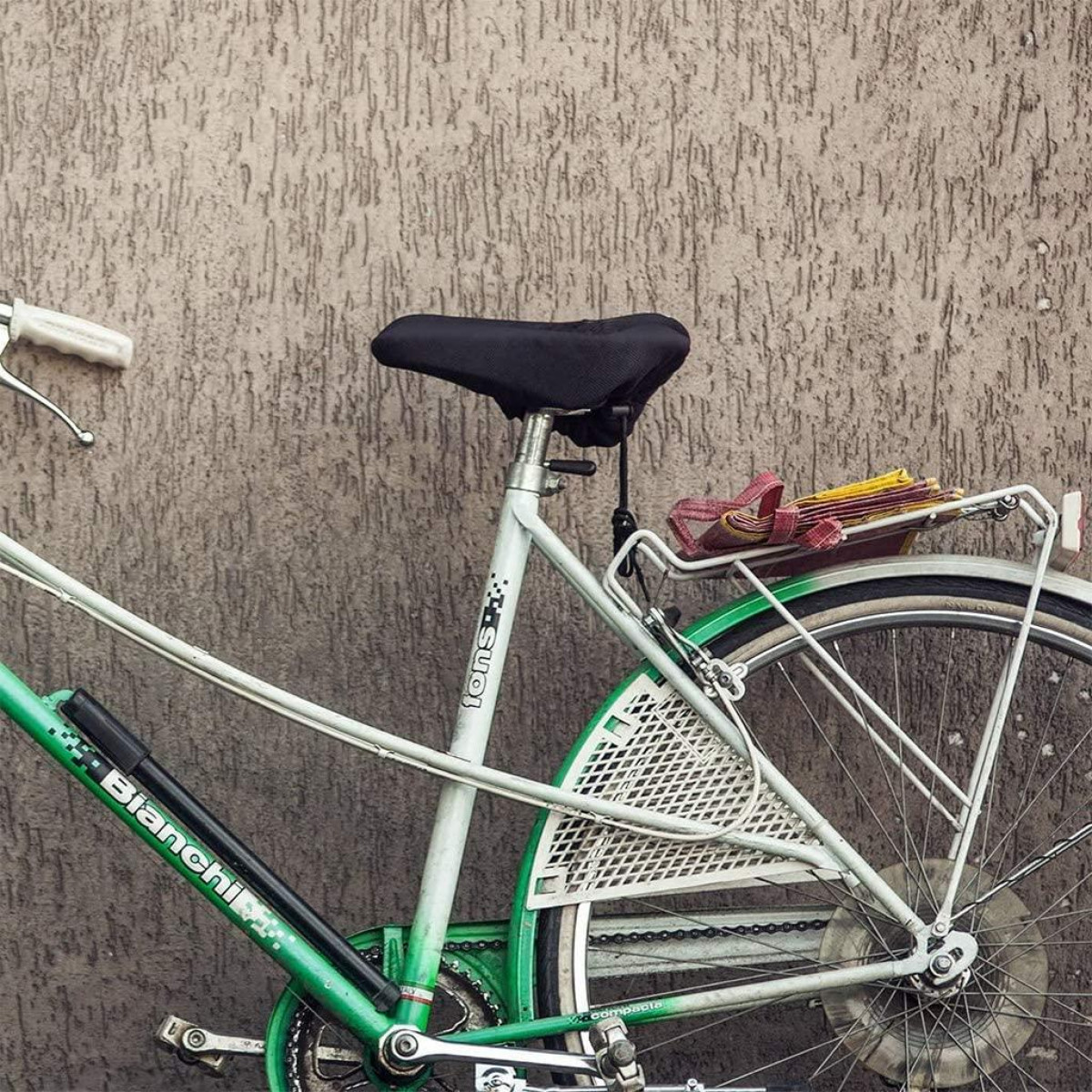 Een groene en witte fiets leunt tegen een getextureerde muur.