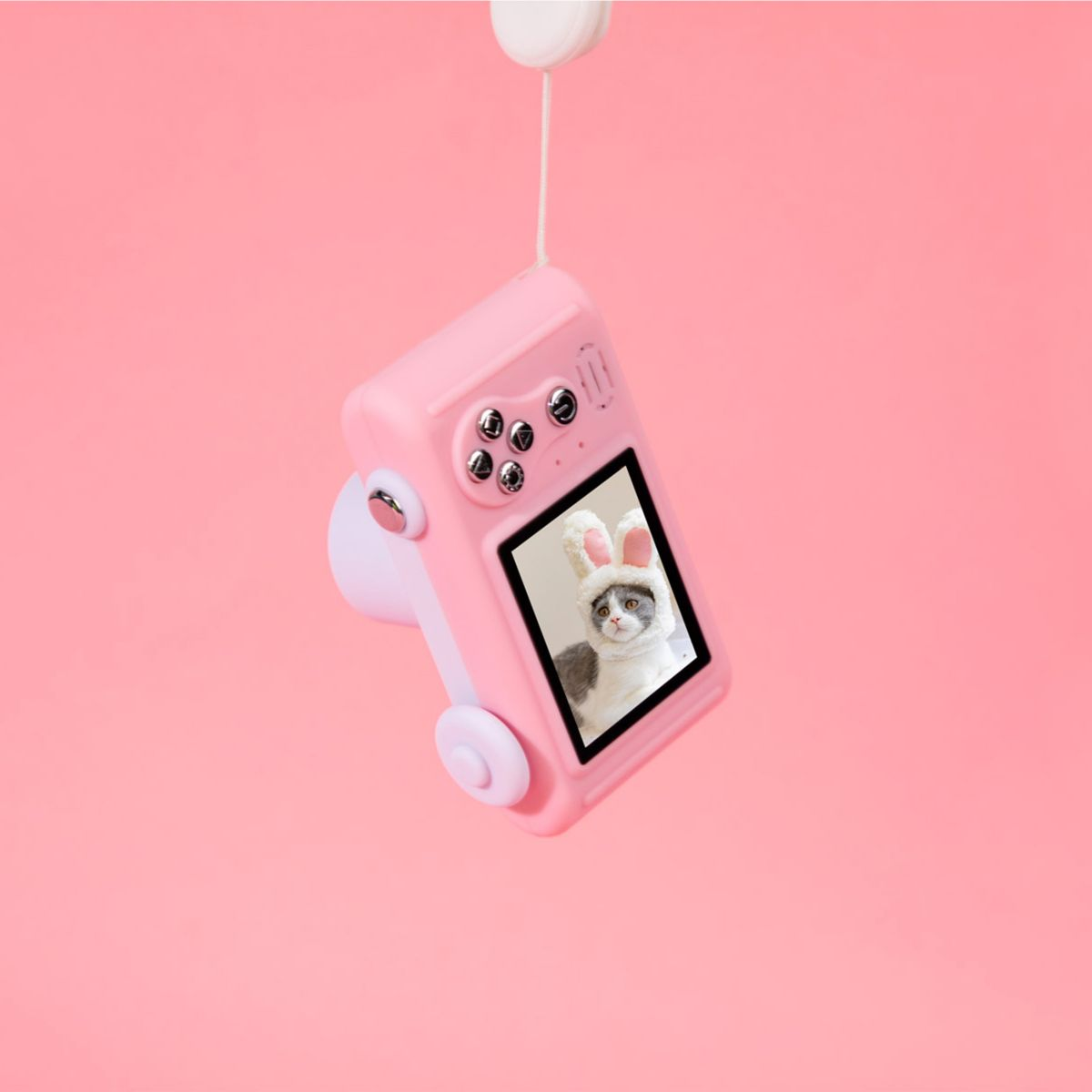 Różowy aparat zabawka z kotem w kapeluszu królika na ekranie, wiszący na sznurku.