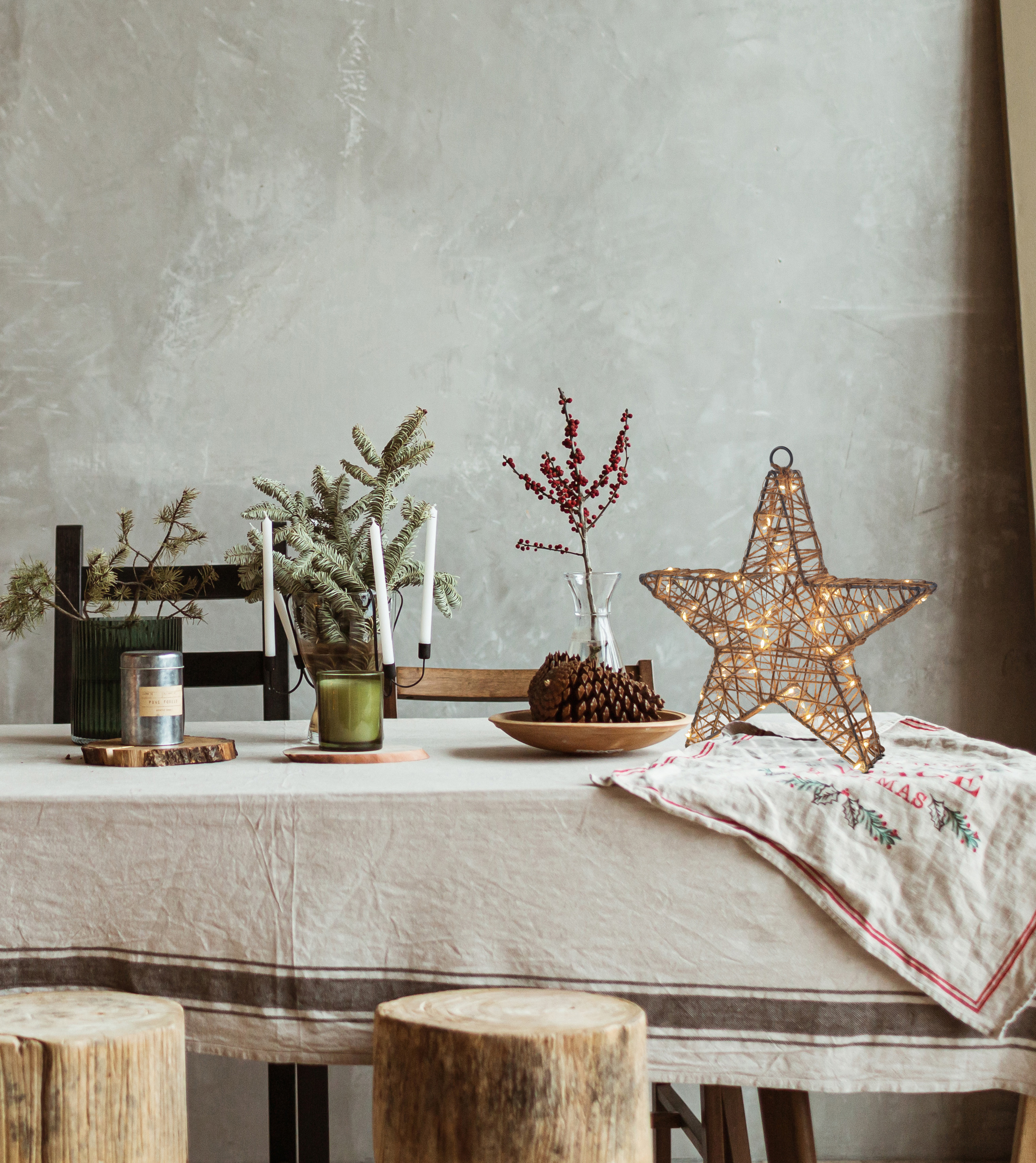 Tisch mit Weihnachtsdeko, Sternlicht, Kerzen und Beeren.