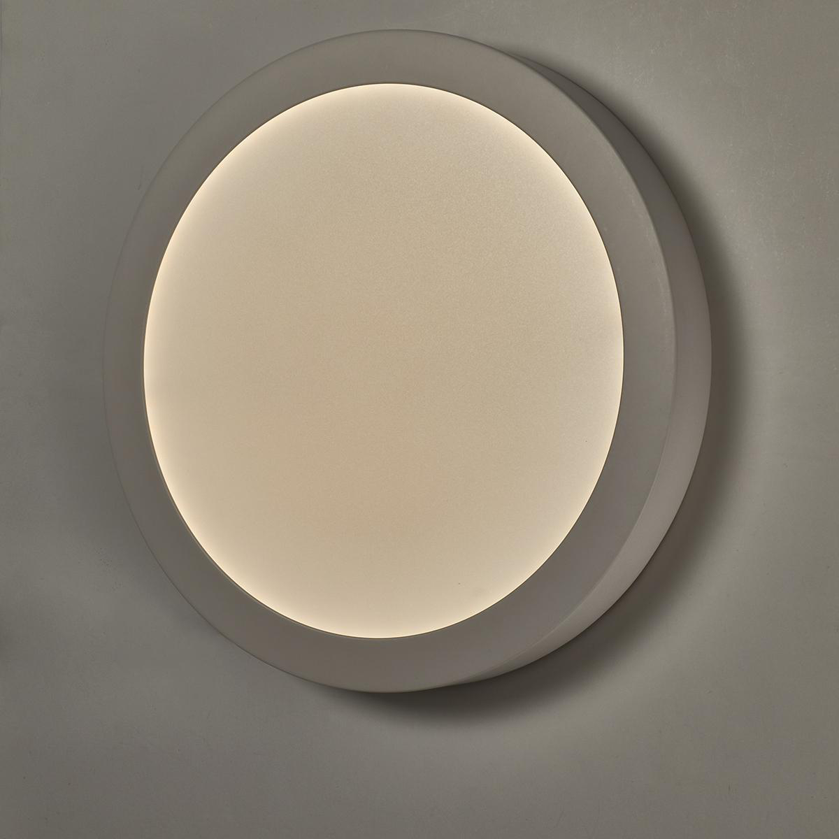 Una luce da soffitto rotonda, bianca, a incasso su una parete bianca.