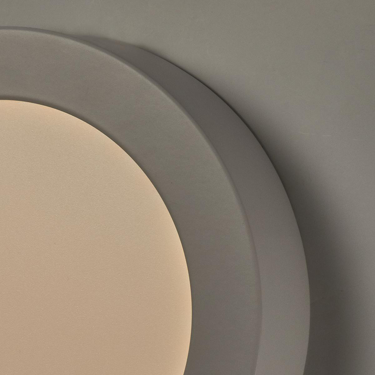 Primo piano di un apparecchio di illuminazione circolare grigio a soffitto, bordi arrotondati.