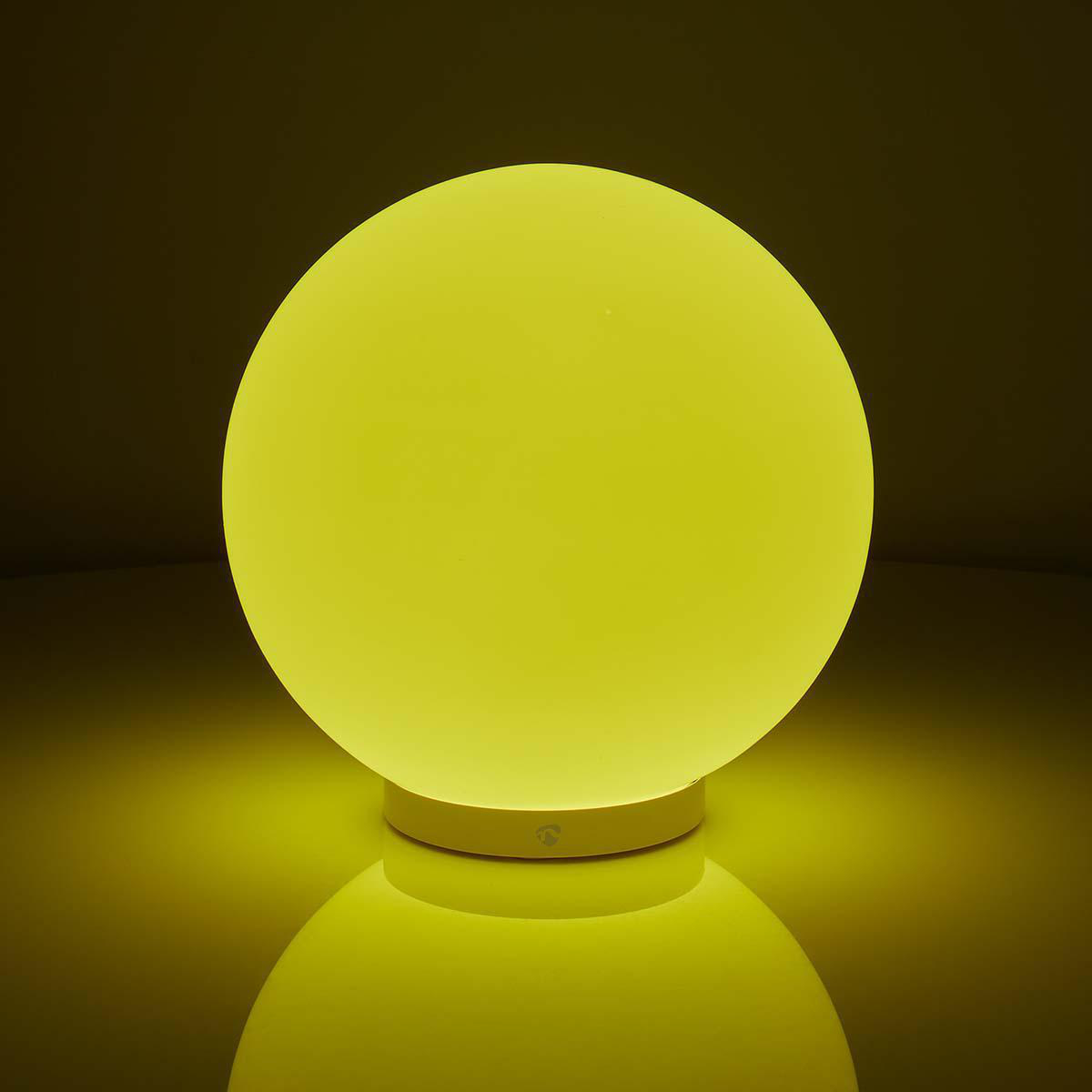Lampada a sfera gialla brillante su superficie riflettente.