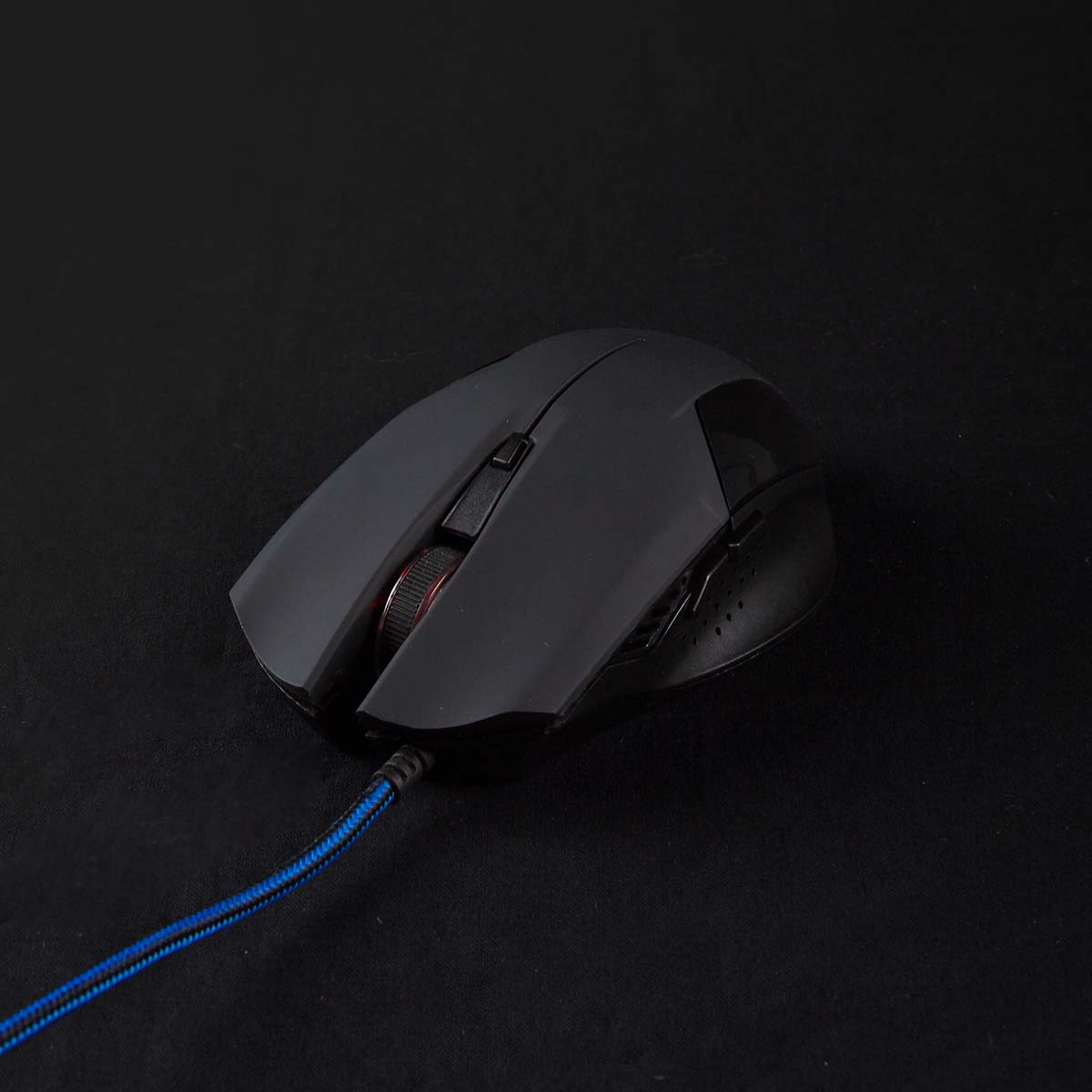 Schwarze Computermaus auf einem schwarzen Mauspadviele Tasten und ein Scrollrad.