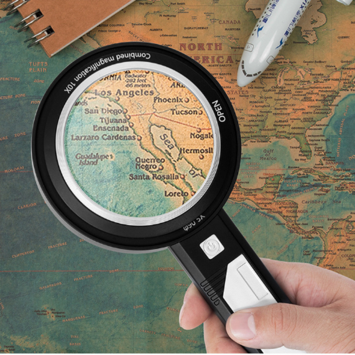 Dłoń trzymająca szkło powiększające nad mapą Ameryki Północnej.