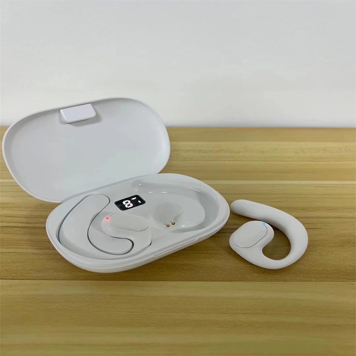 Auriculares inalámbricos blancos en un estuche de carga, y un auricular individual al lado.