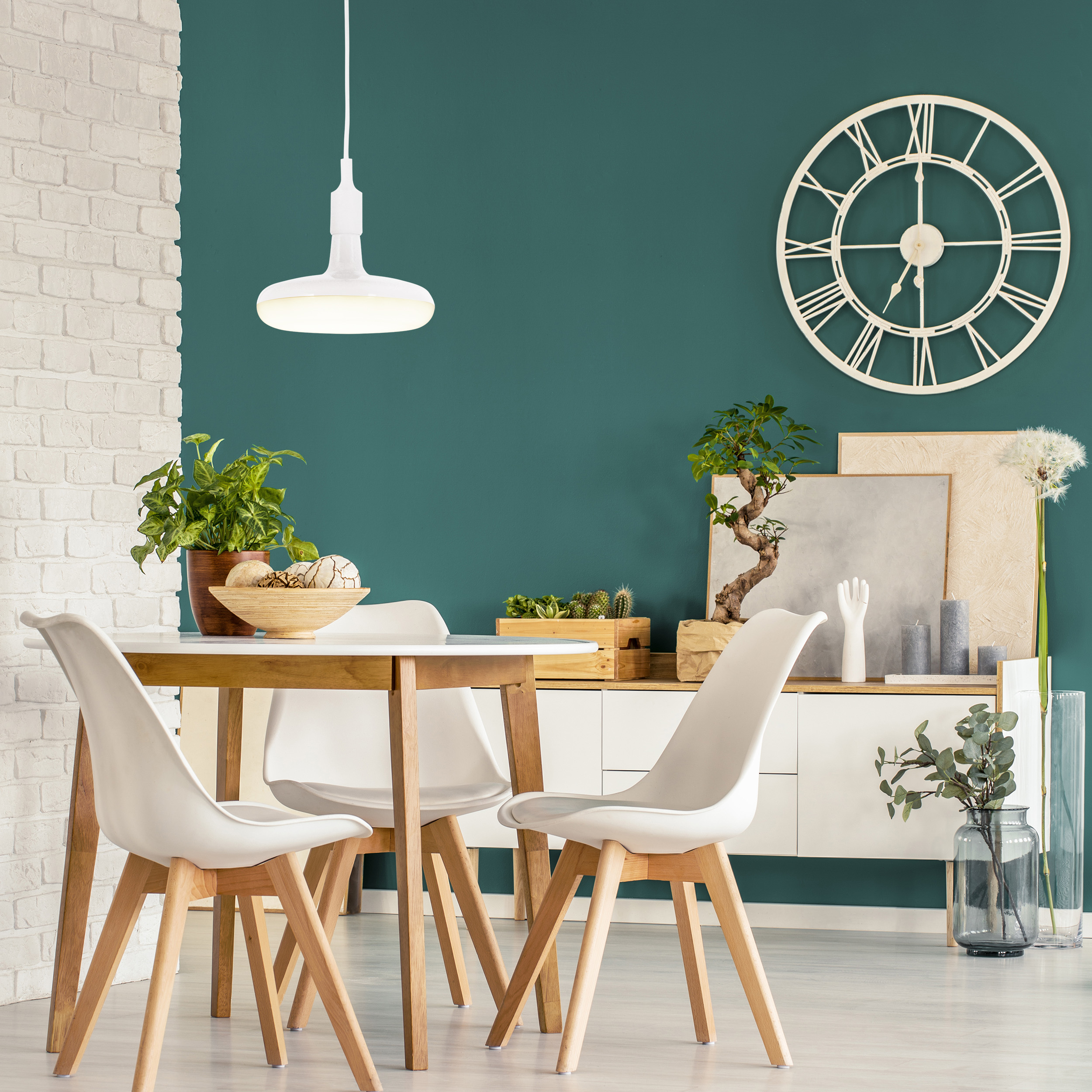 Esszimmer mit Tisch, Stühlen, Pflanzen und einer Uhr an der Wand.