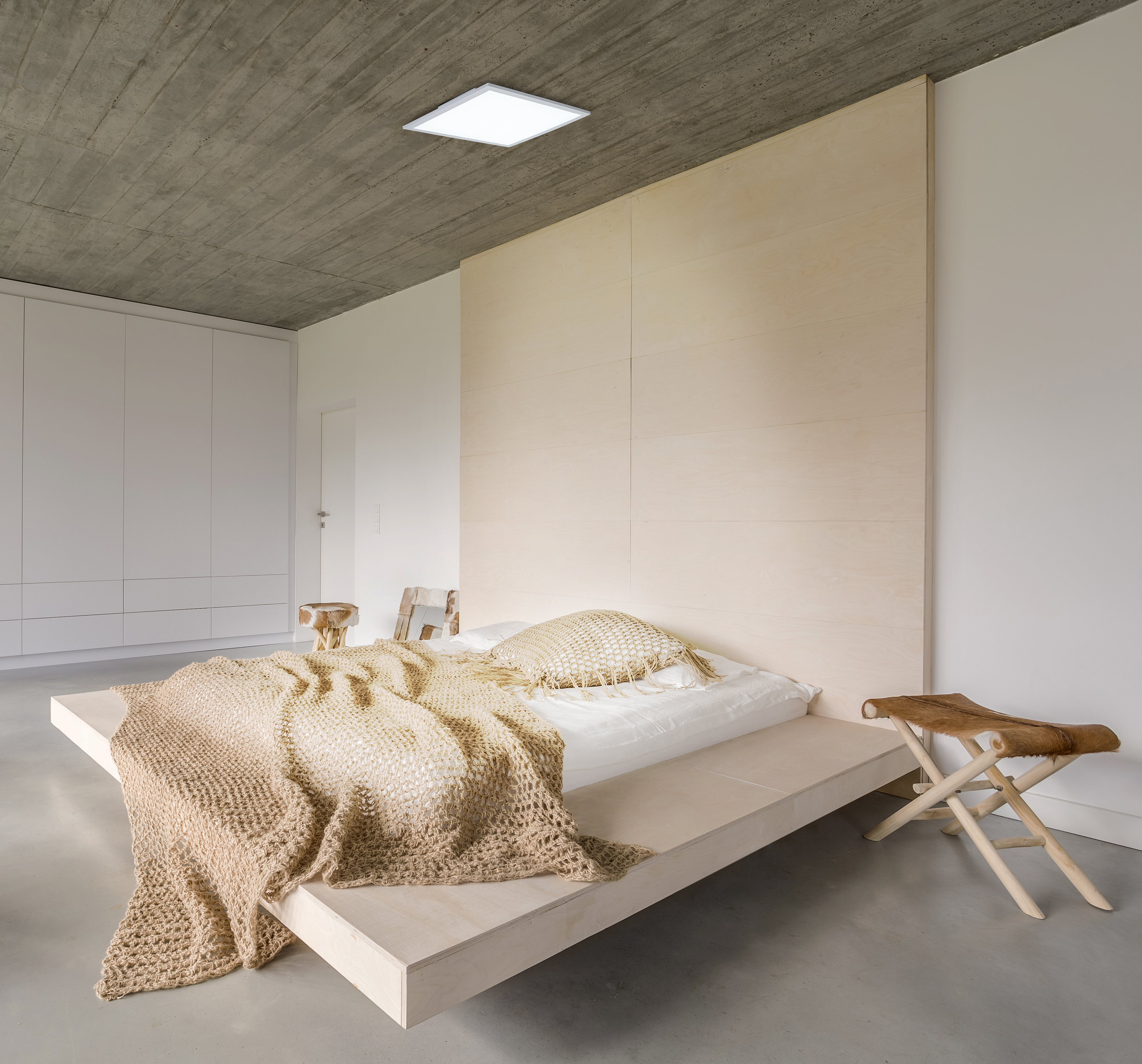 Modernes Schlafzimmer mit Holzbett, hellbrauner Decke und Betondecke.