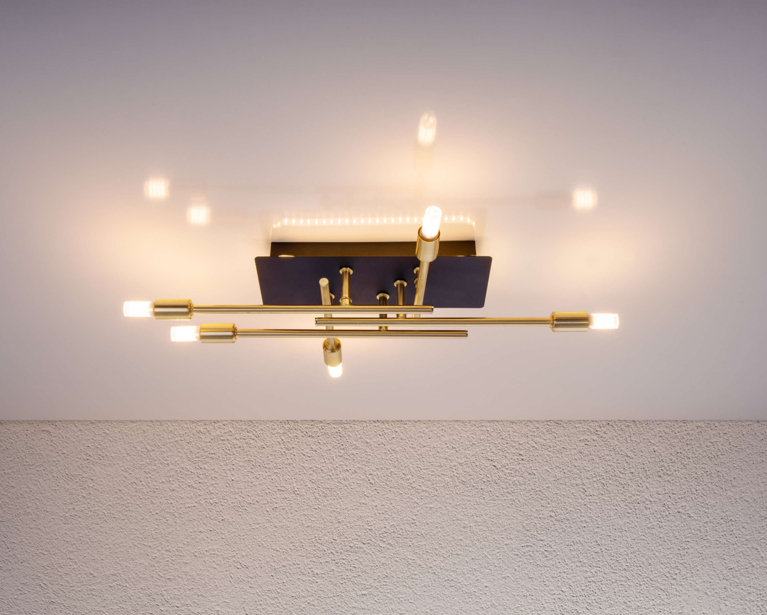 Decke mit moderner gold-schwarzer Leuchte und strukturierter weißer Wand.