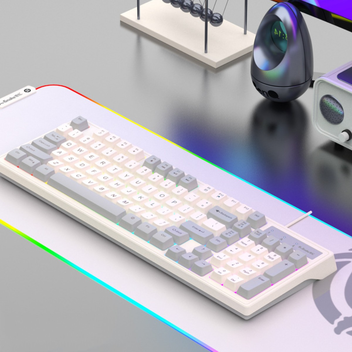 Weiße Tastatur auf bunter Matte. Auf dem Schreibtisch befinden sich ein Lautsprecher und eine Dekoration.