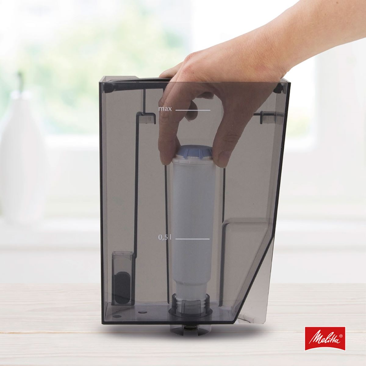 Hand setzt Filter in einen transparenten Wasserfilterbehälter mit Melitta-Logo ein.