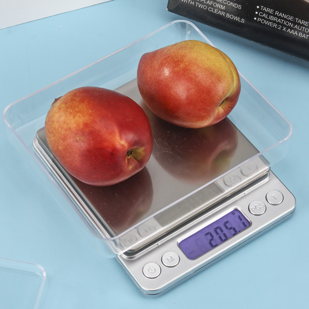 Eine digitale Waage mit zwei Pfirsichen in einer durchsichtigen Kunststoffschale. Die Waage zeigt 205,1 an.